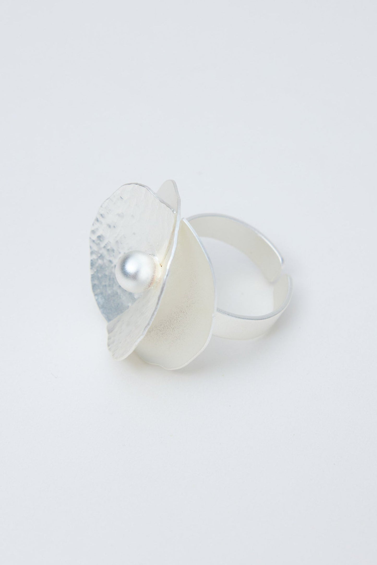Silver ring with a textured band and pearl on a light gray background