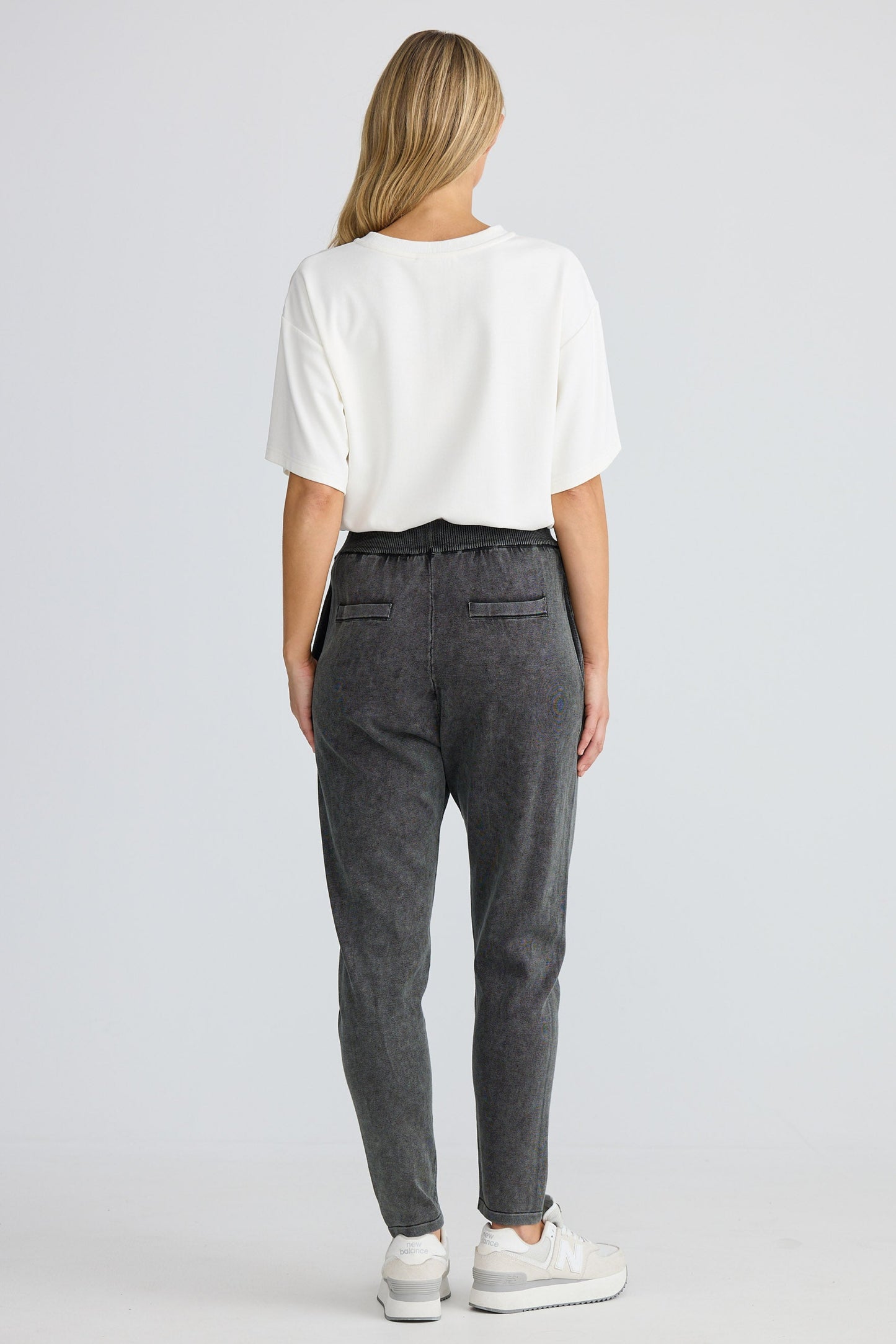 Person wearing a white top and gray pants on a white background