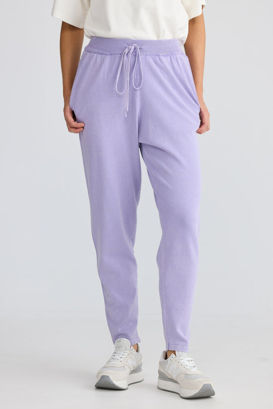 Person wearing lavender jogger pants and white sneakers on a light gray background