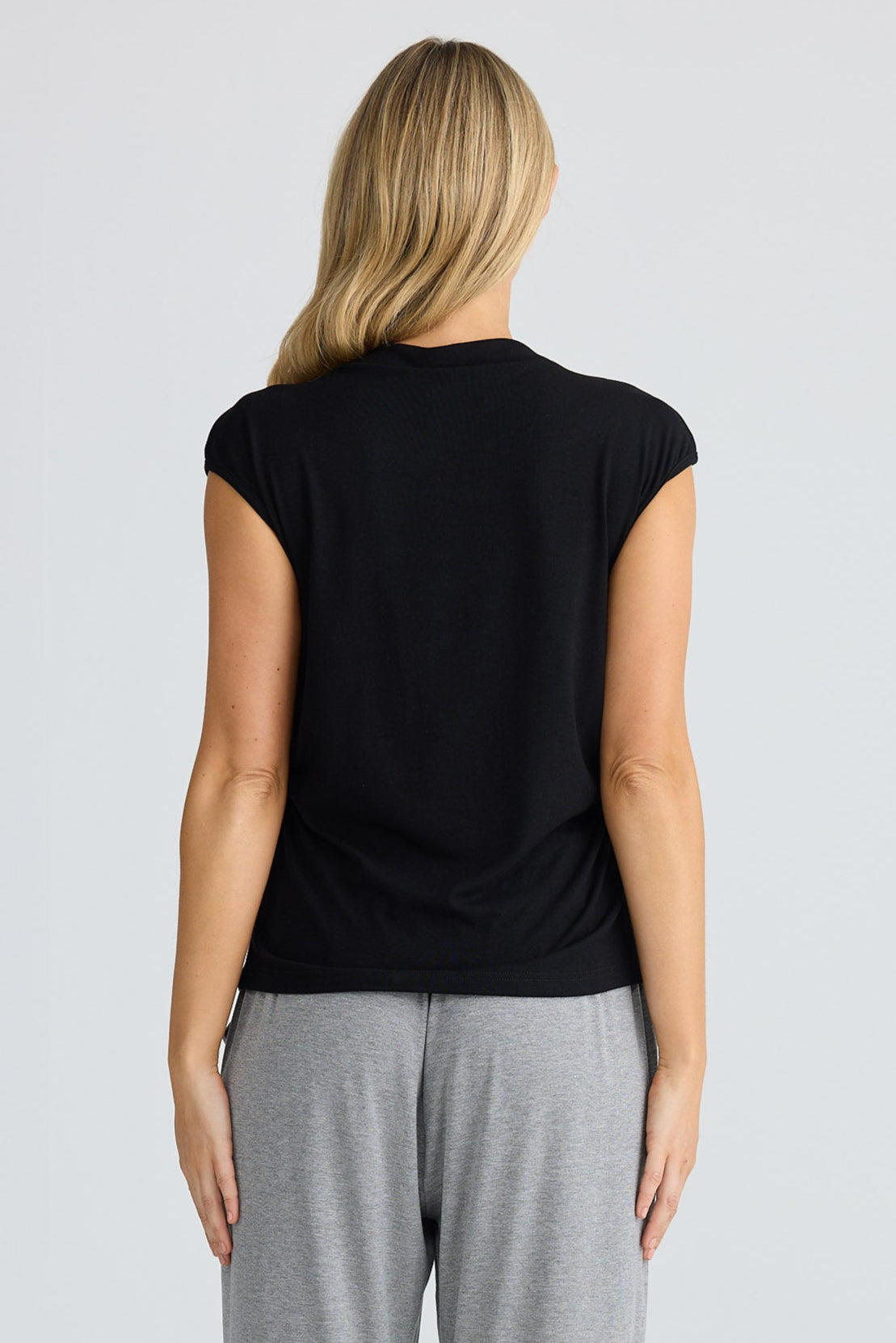 Woman wearing a black t-shirt and gray pants on a white background