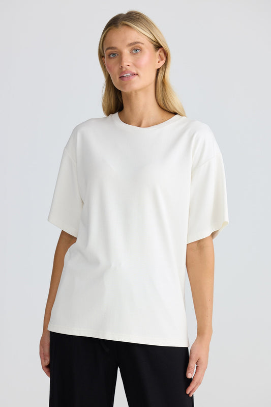 Woman wearing a white blouse and black pants on a plain background