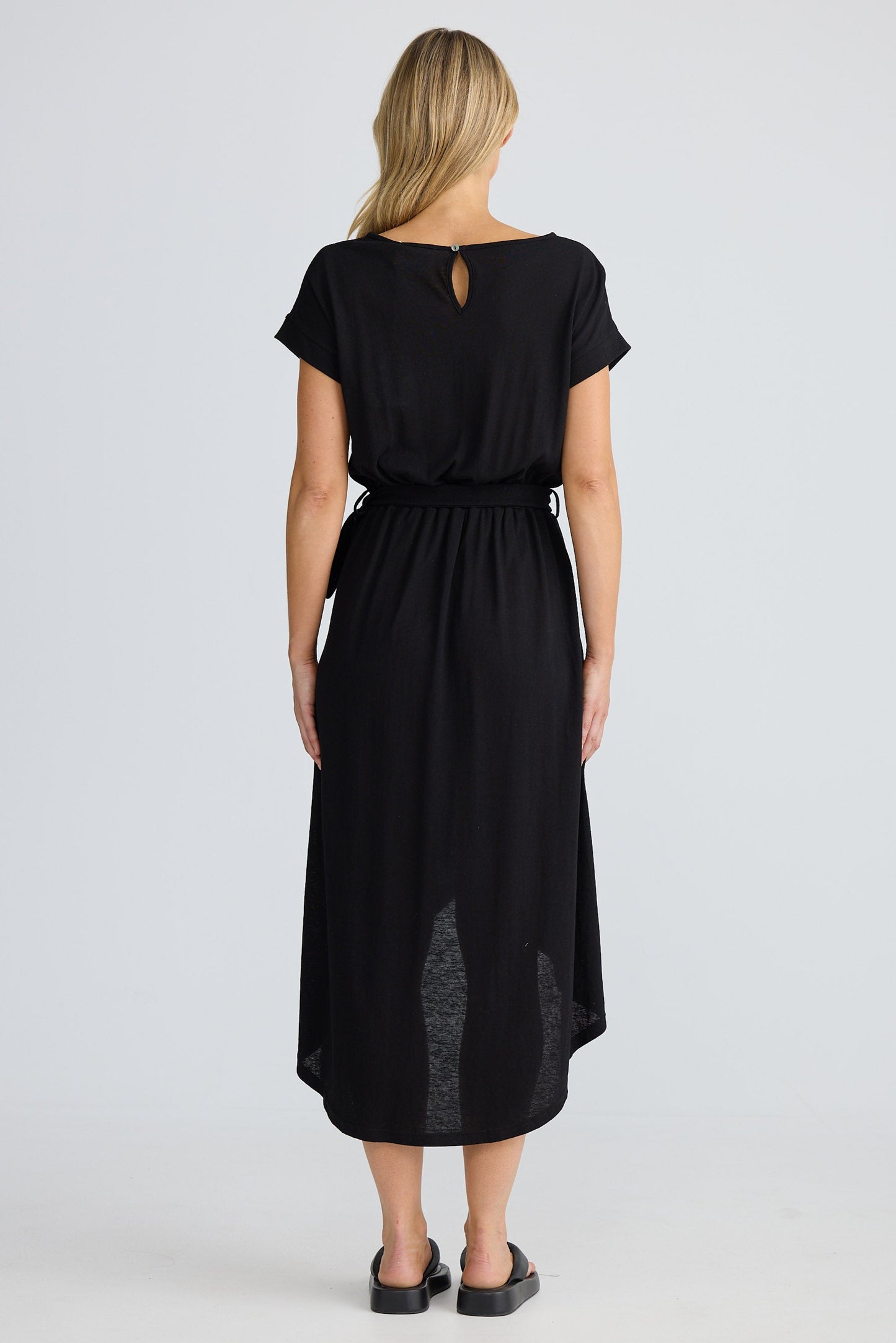 Woman wearing a black dress with a belt on a white background