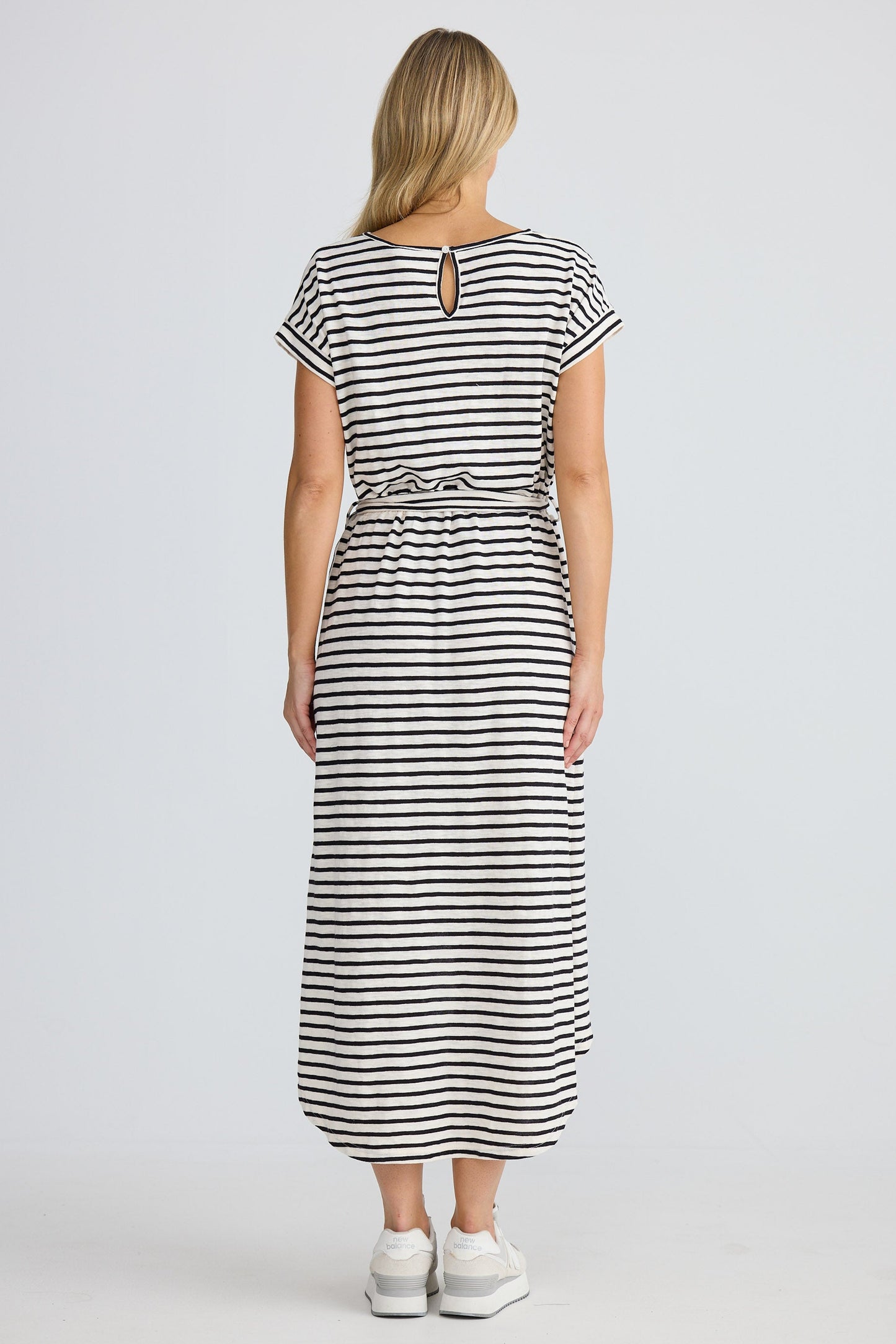 Woman wearing a black and white striped dress on a plain background