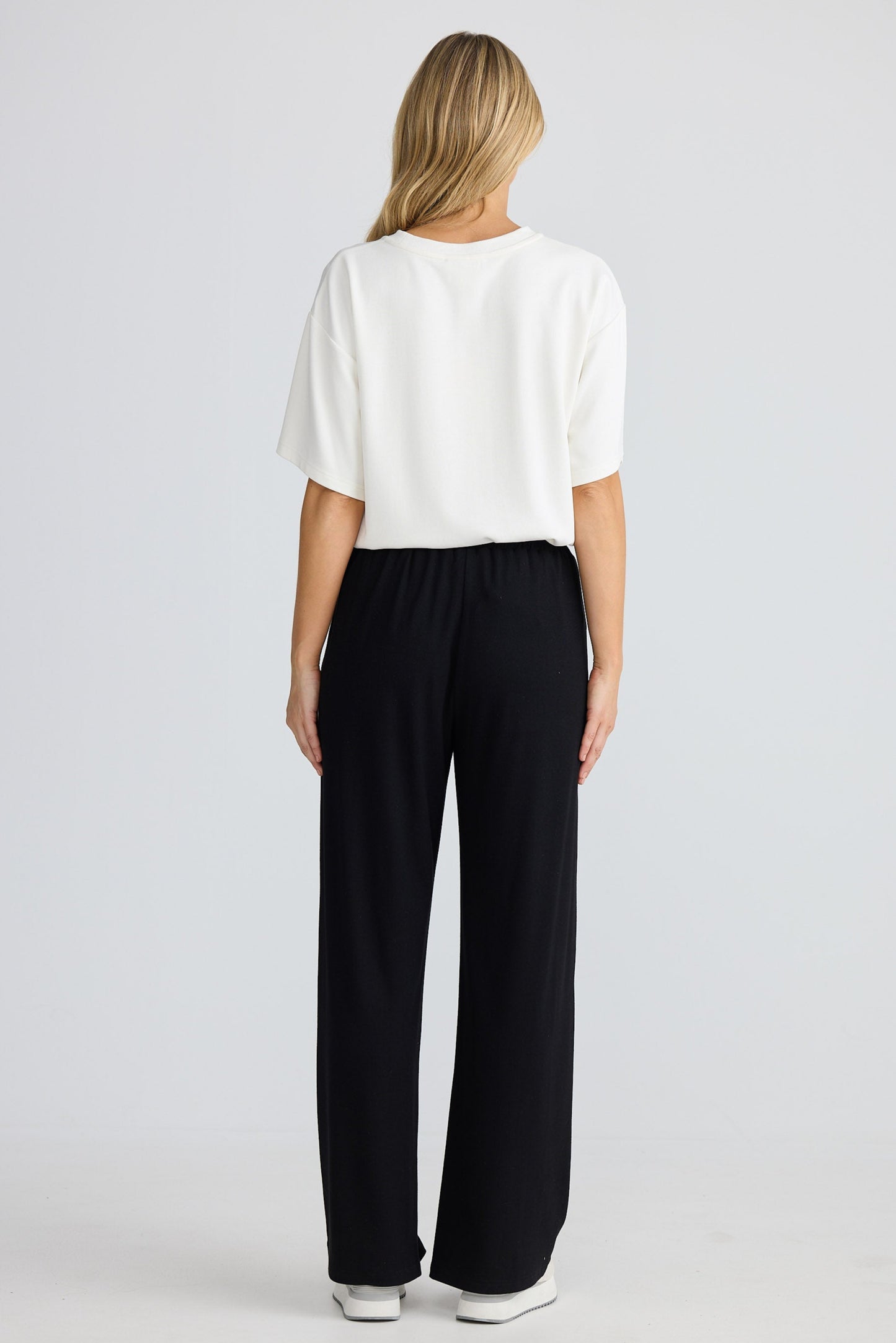 Woman wearing a white top and black pants on a white background