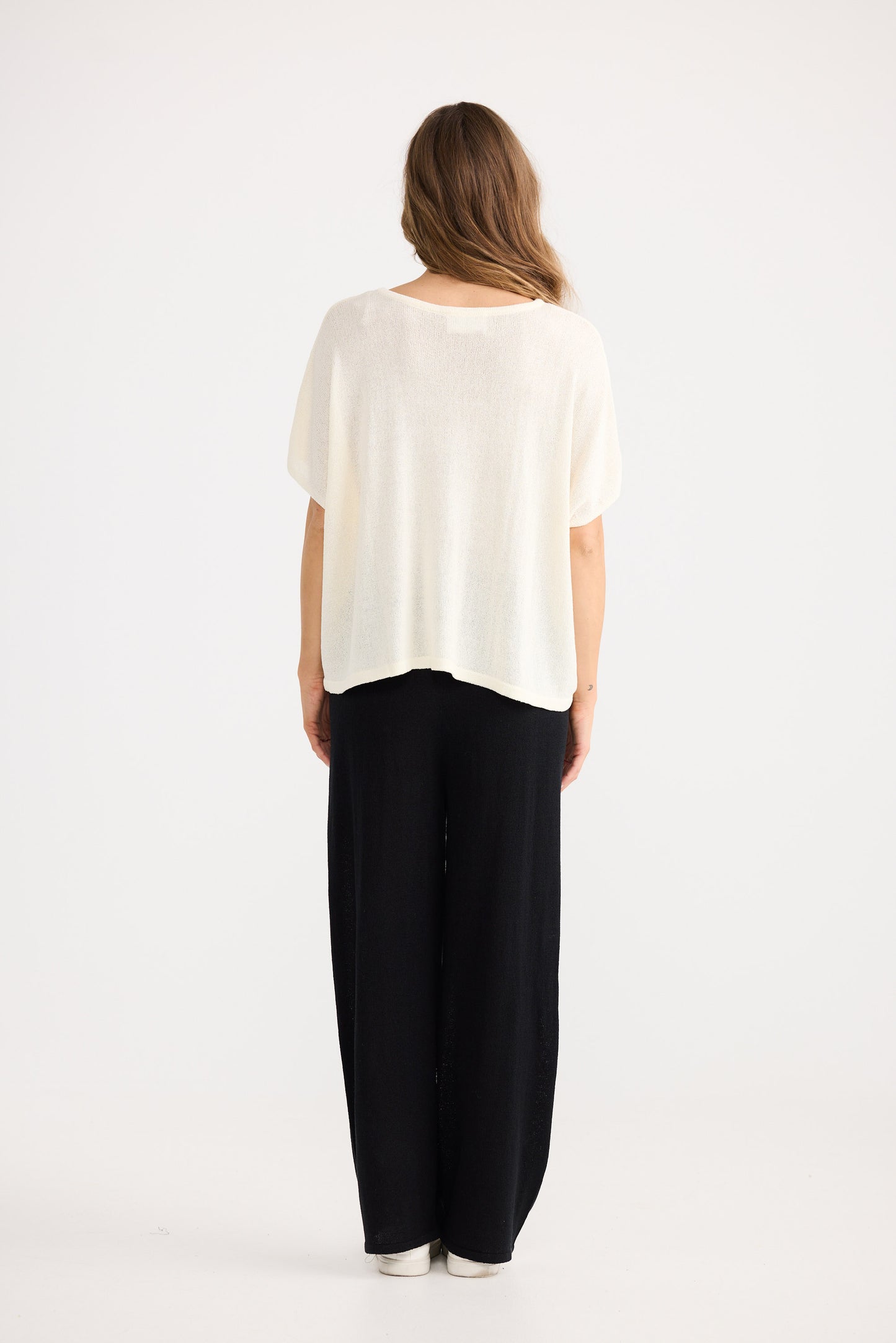 Woman wearing a white top and black pants on a white background
