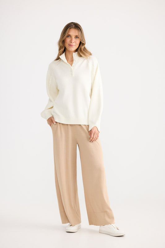 Woman wearing a white blouse and beige pants on a white background
