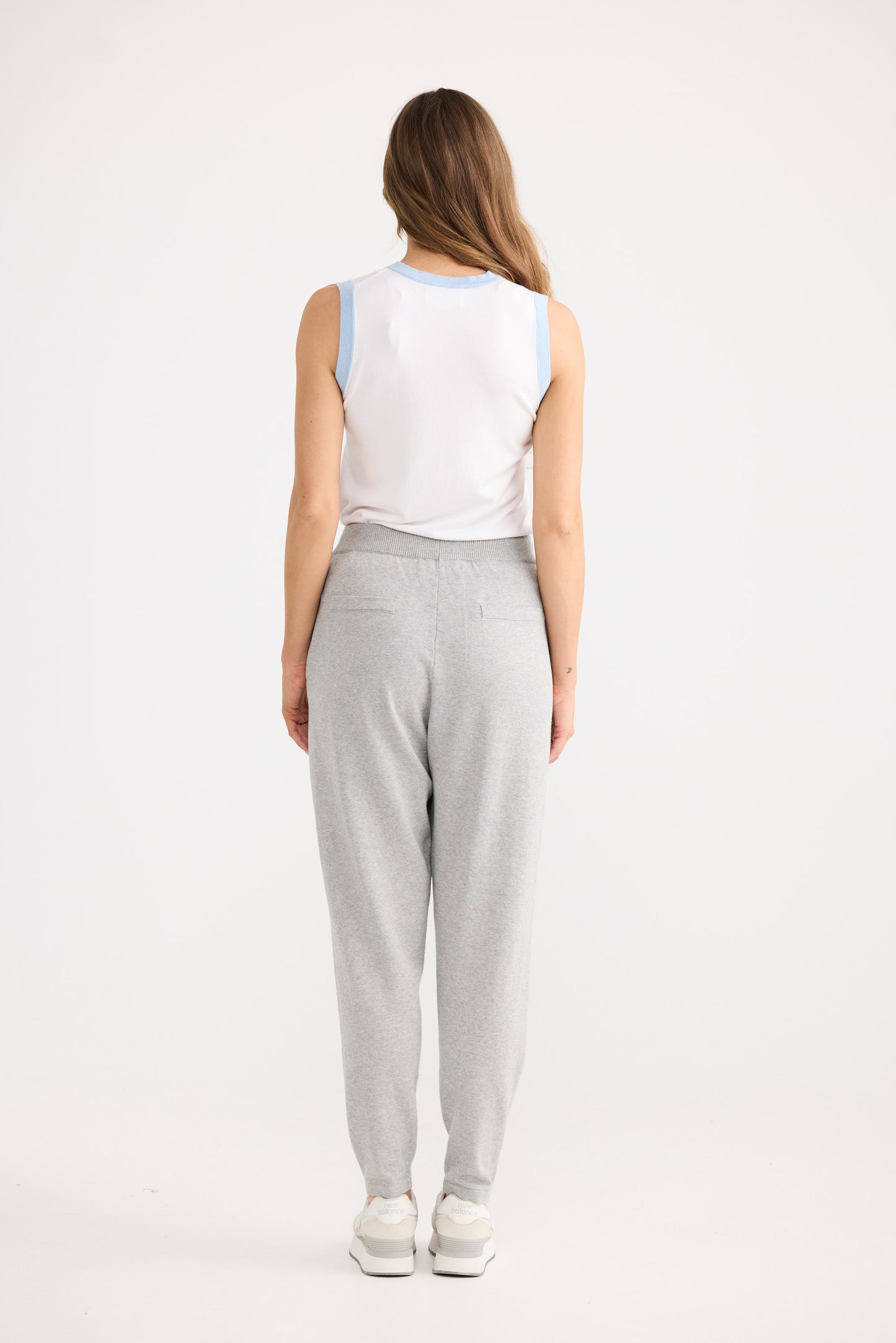 Person wearing grey pants and a white top on a white background