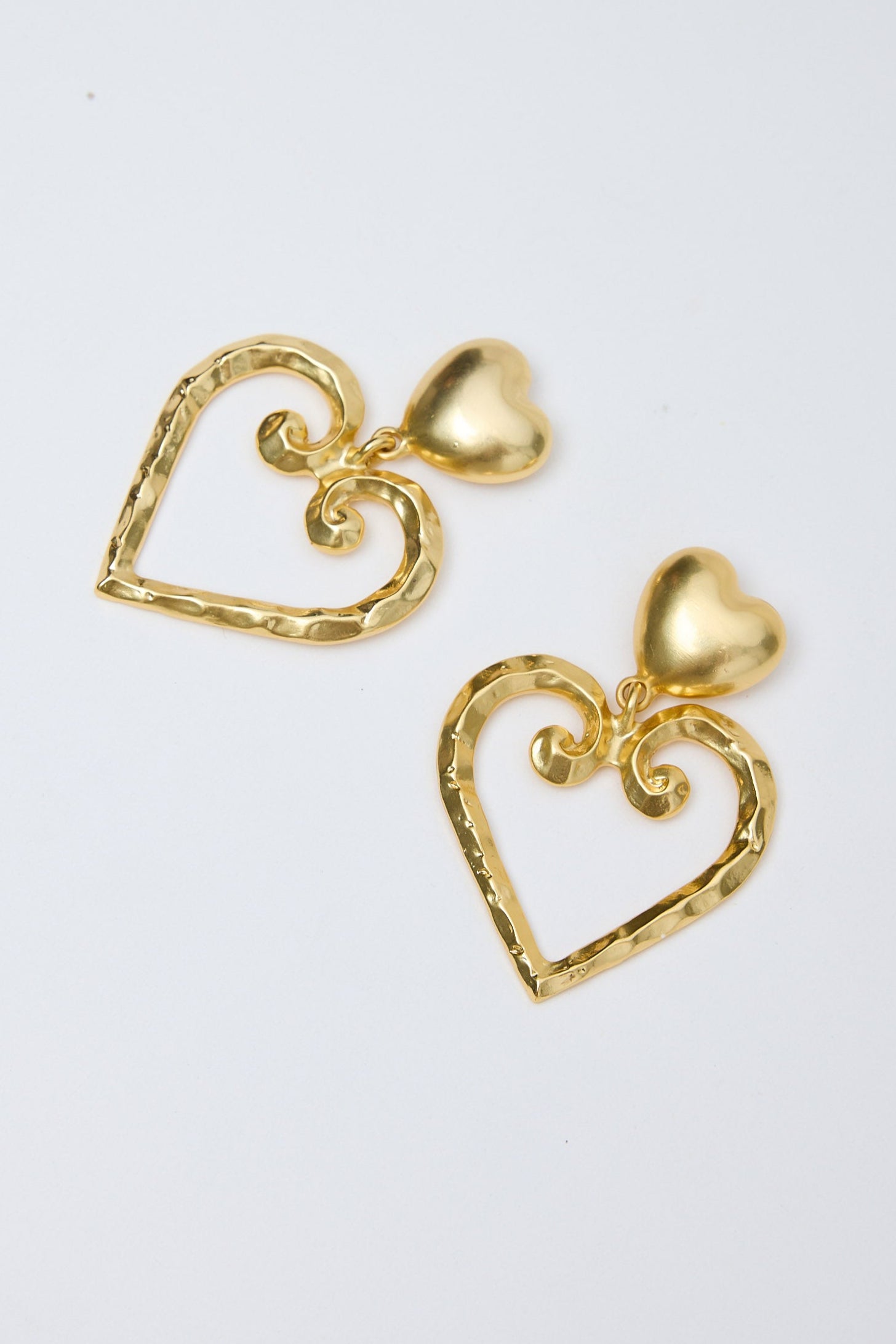 Gold heart-shaped earrings on a light gray background