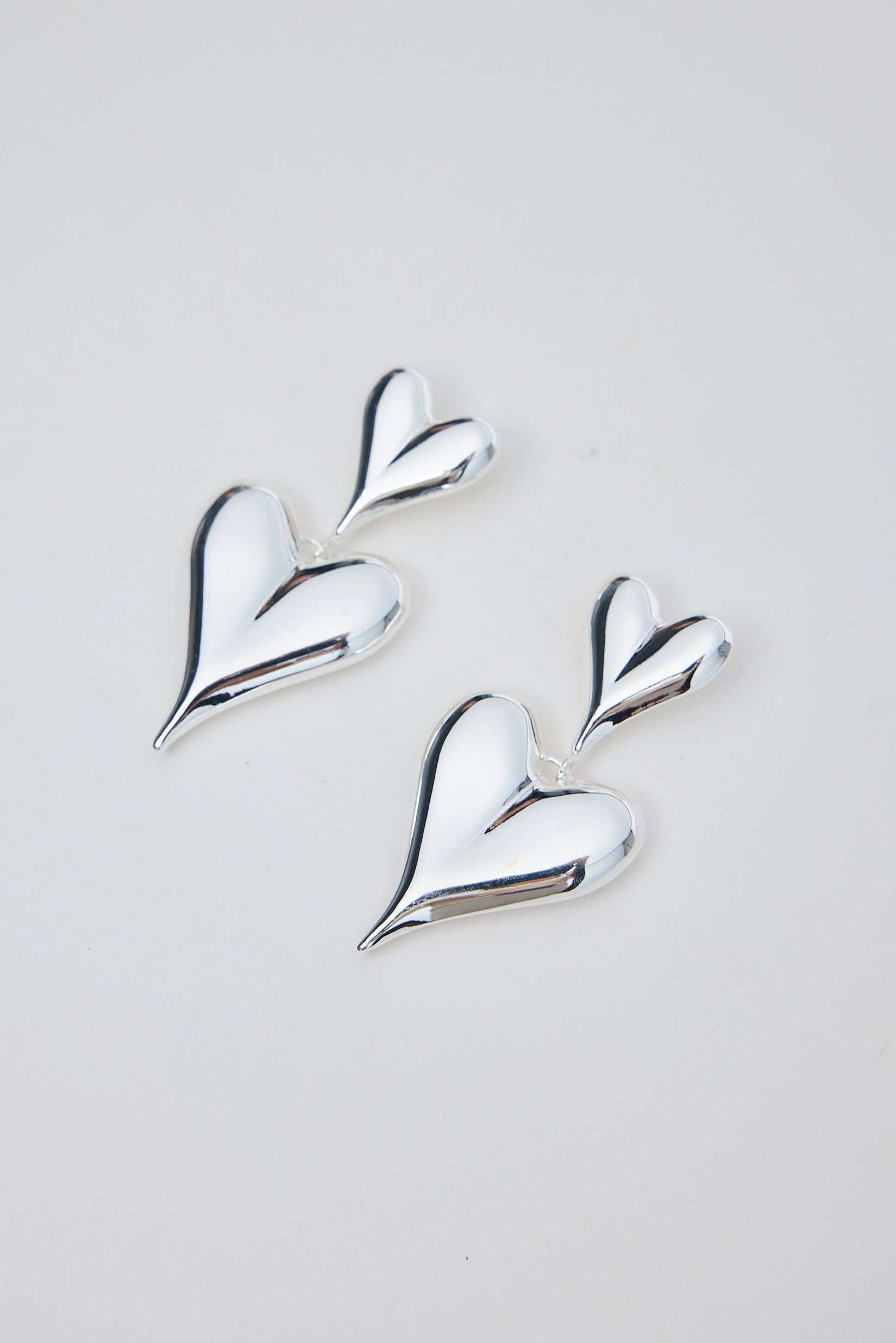 Silver heart-shaped earrings on a light gray background
