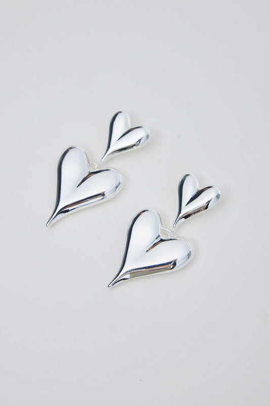 Silver heart-shaped earrings on a light gray background
