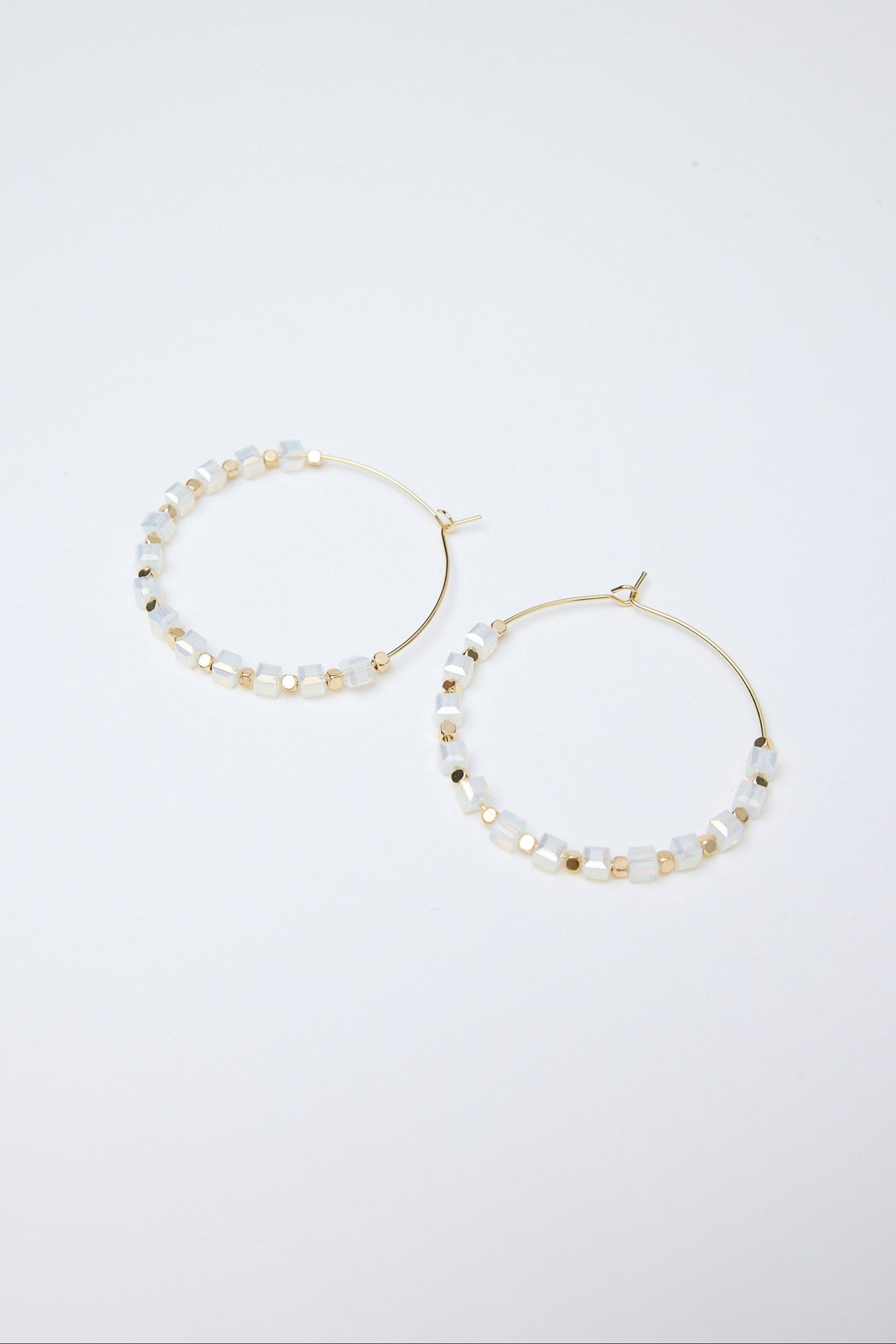 Pair of hoop earrings with pearl-like beads on a white background