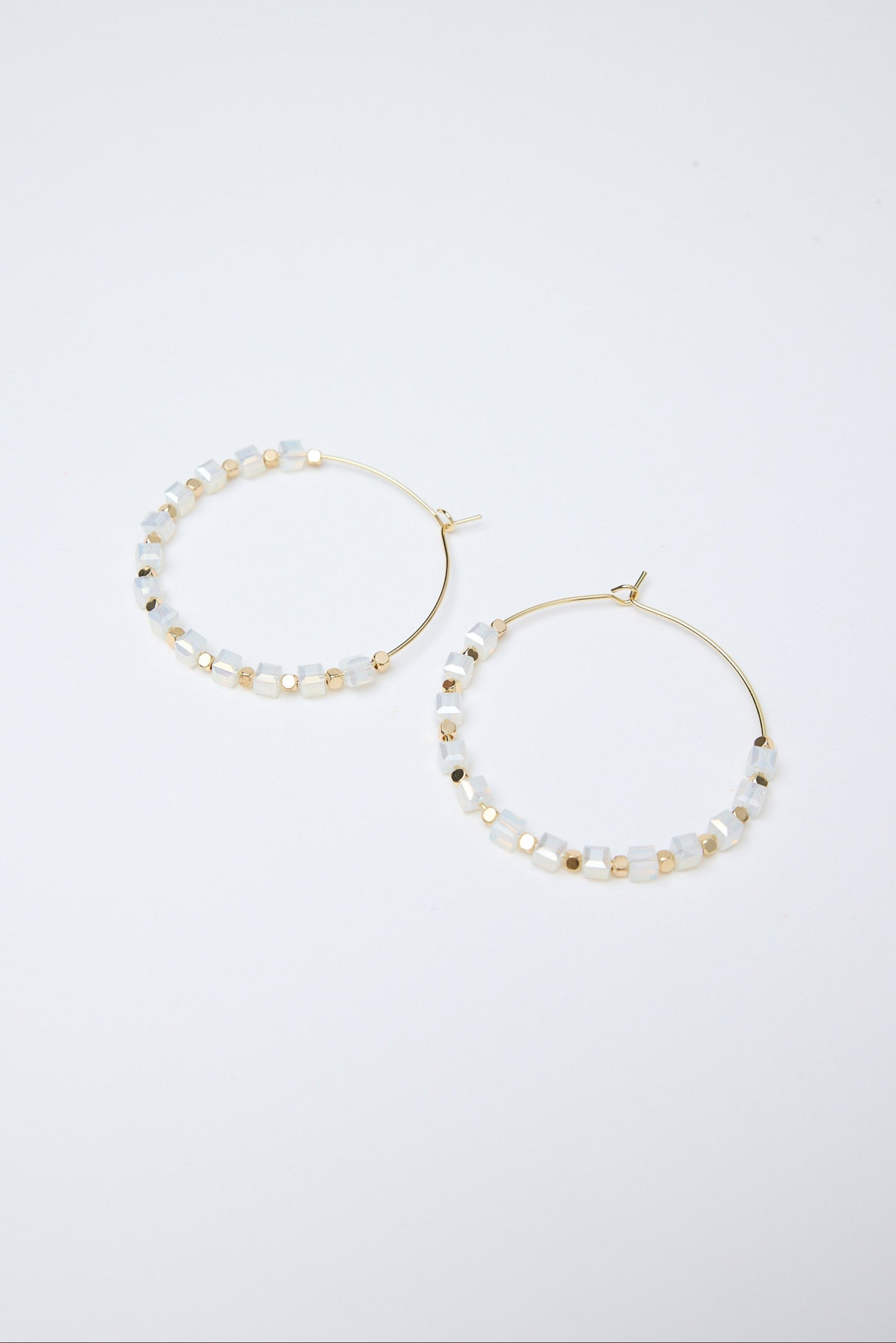 Pair of hoop earrings with pearl-like beads on a white background