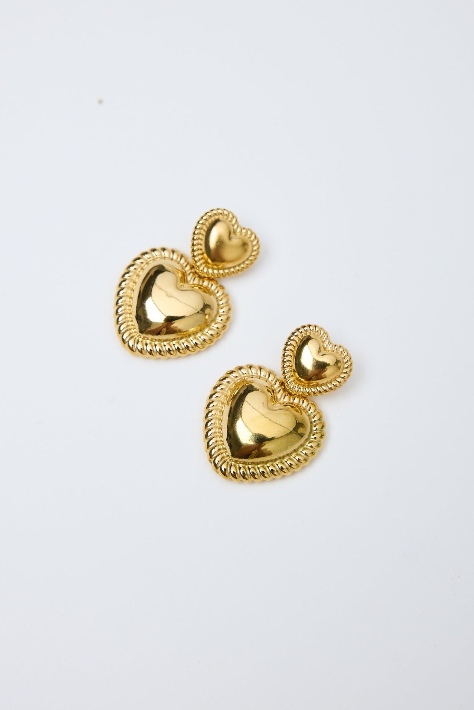 Gold heart-shaped earrings on a white background