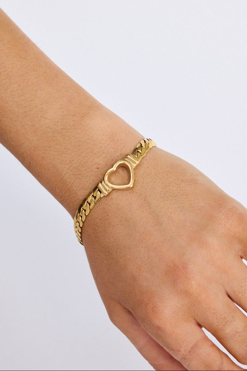 Model wearing Hearts Bracelet in gold with delicate heart link detailing, on-wrist view on neutral background