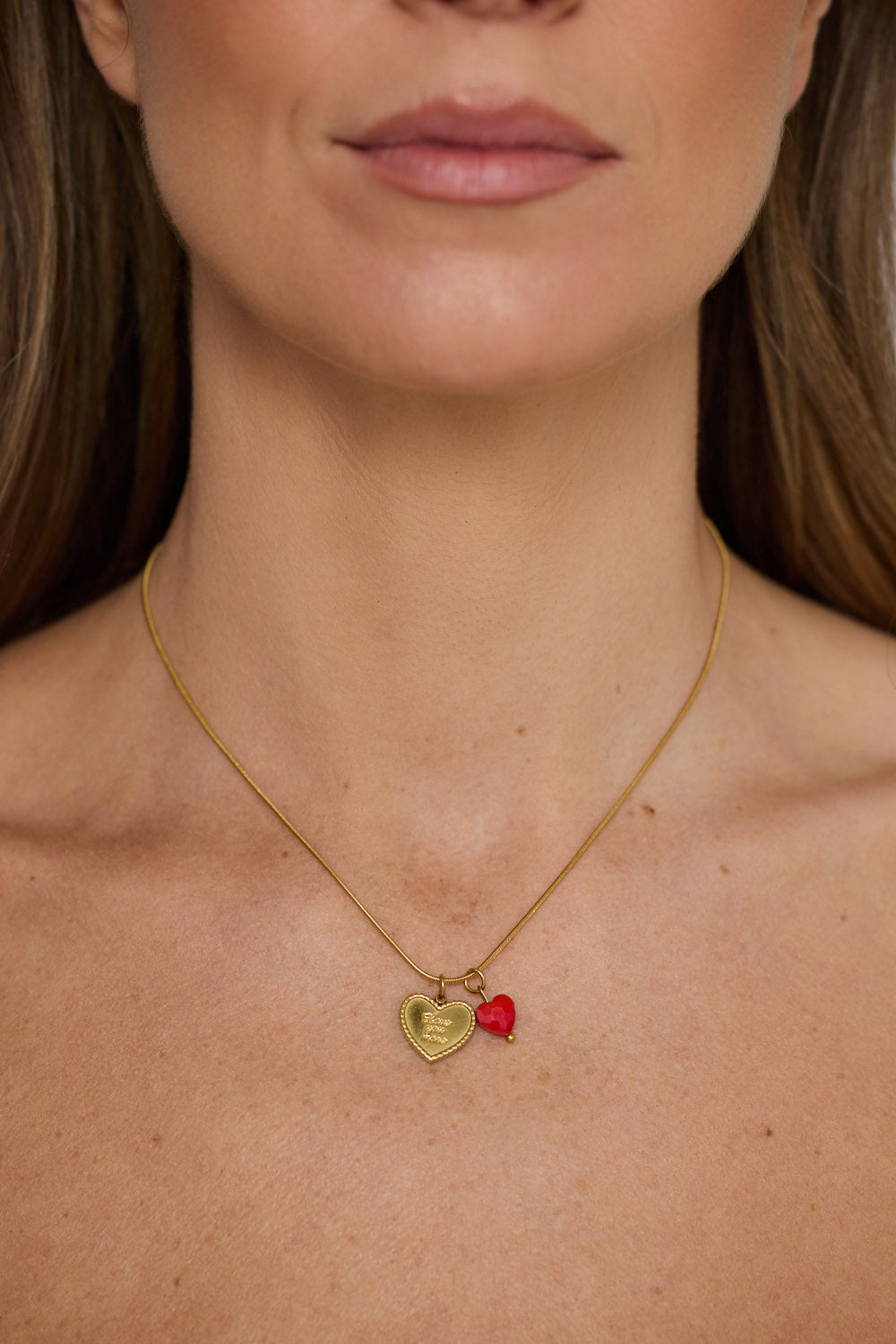 Love You More Necklace in gold with heart charm detailing, pendant close-up view on neutral background