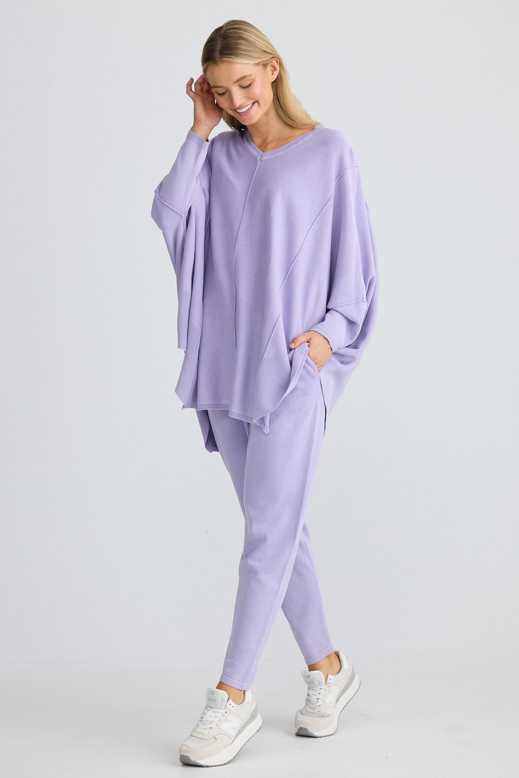 Woman wearing a lavender outfit with a matching top and pants on a white background