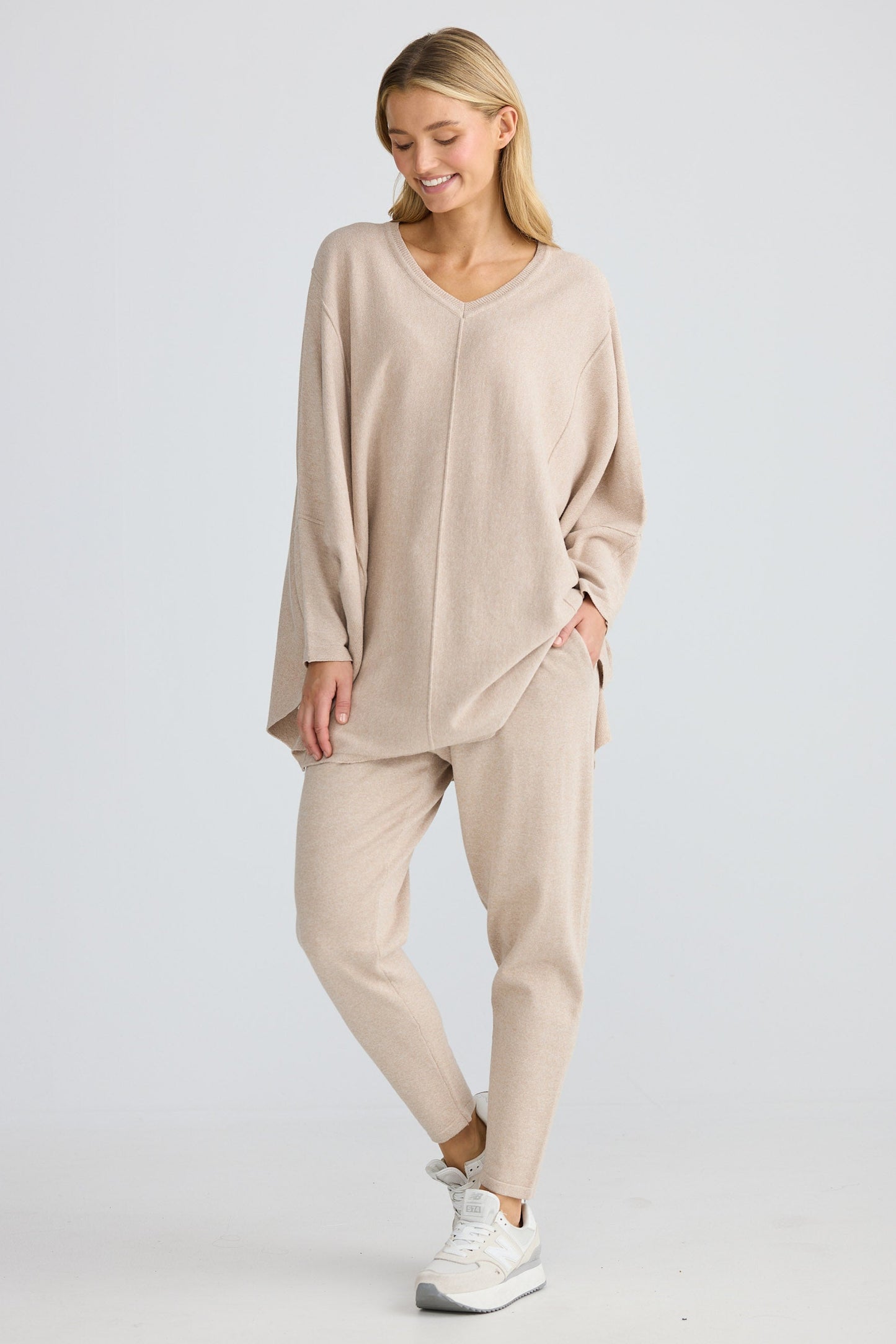 Woman wearing a beige outfit with a matching top and pants on a white background