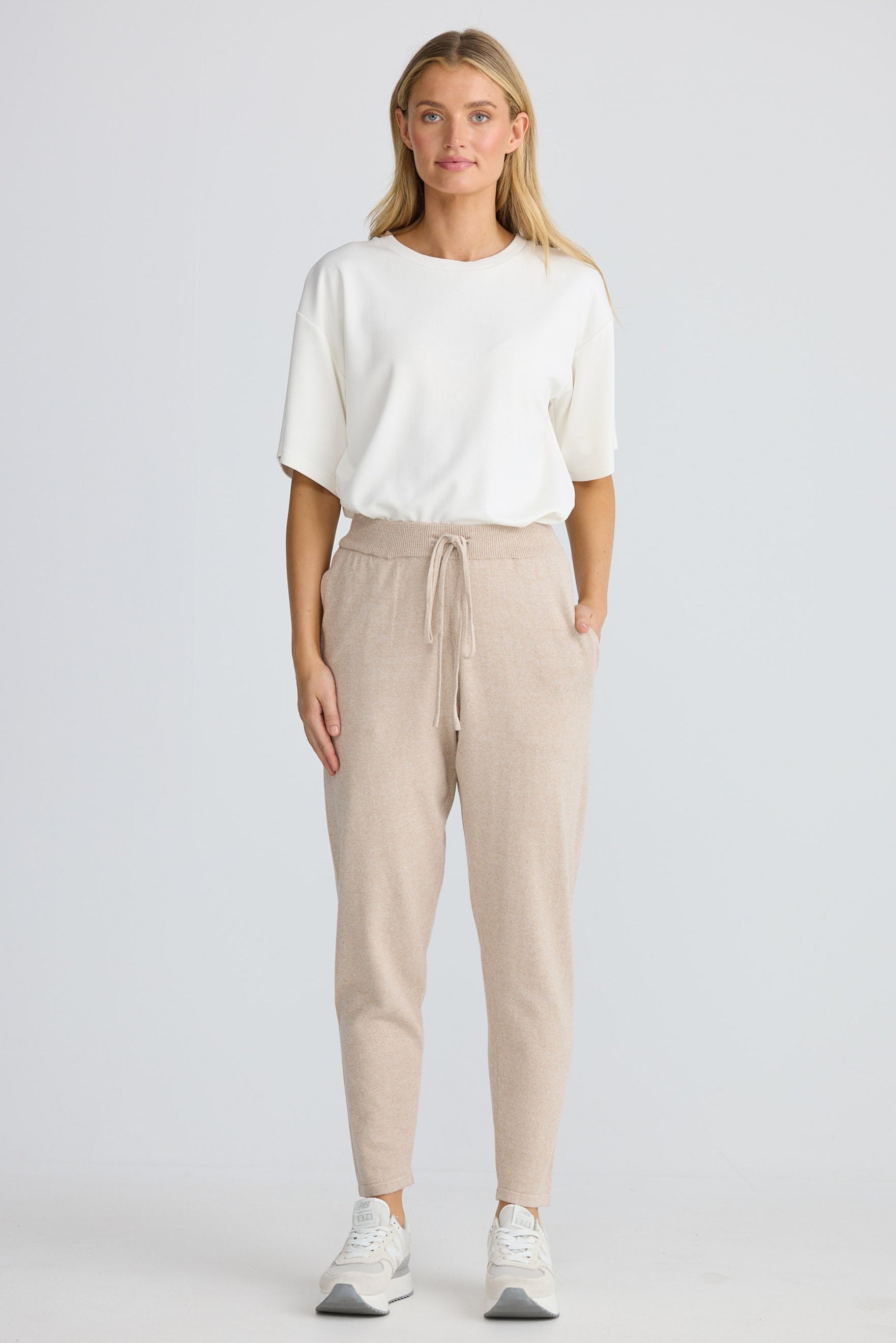 Woman wearing a white top and beige pants on a white background
