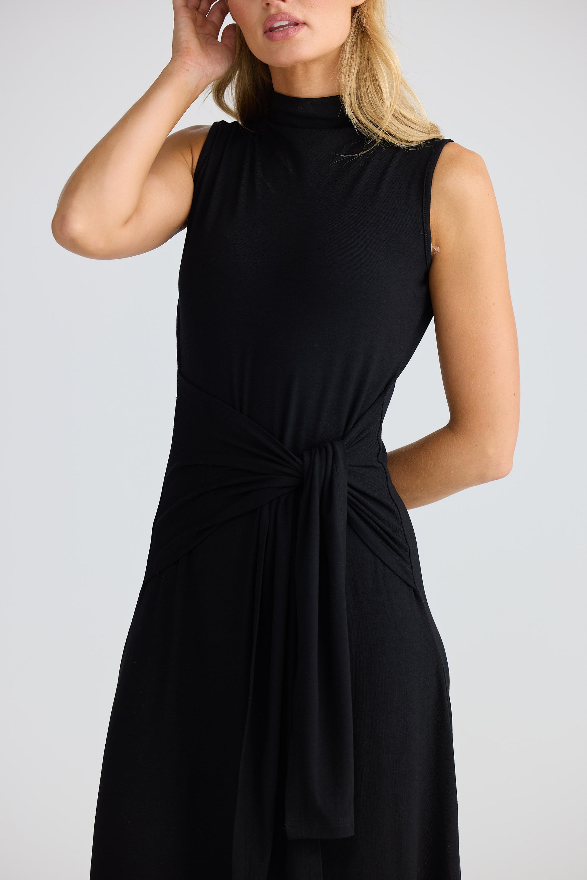 Woman wearing a black sleeveless dress against a plain background