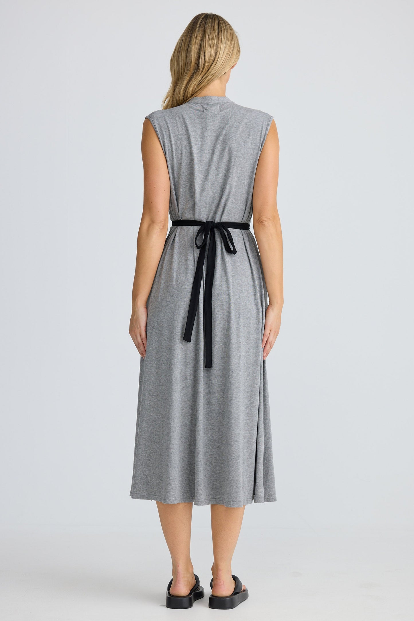 Woman wearing a gray dress with a black belt on a white background