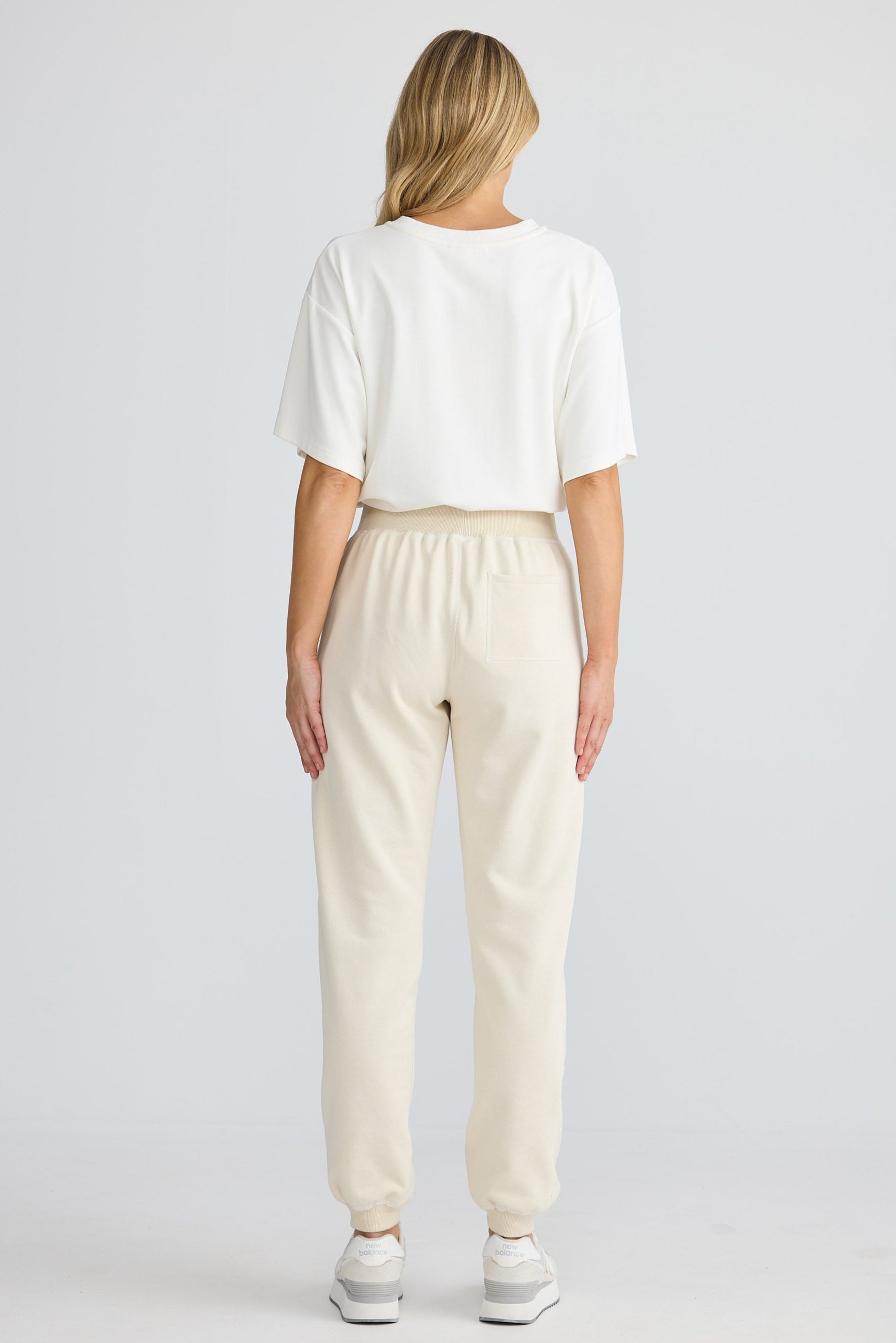 Person wearing a white t-shirt and beige pants on a plain background