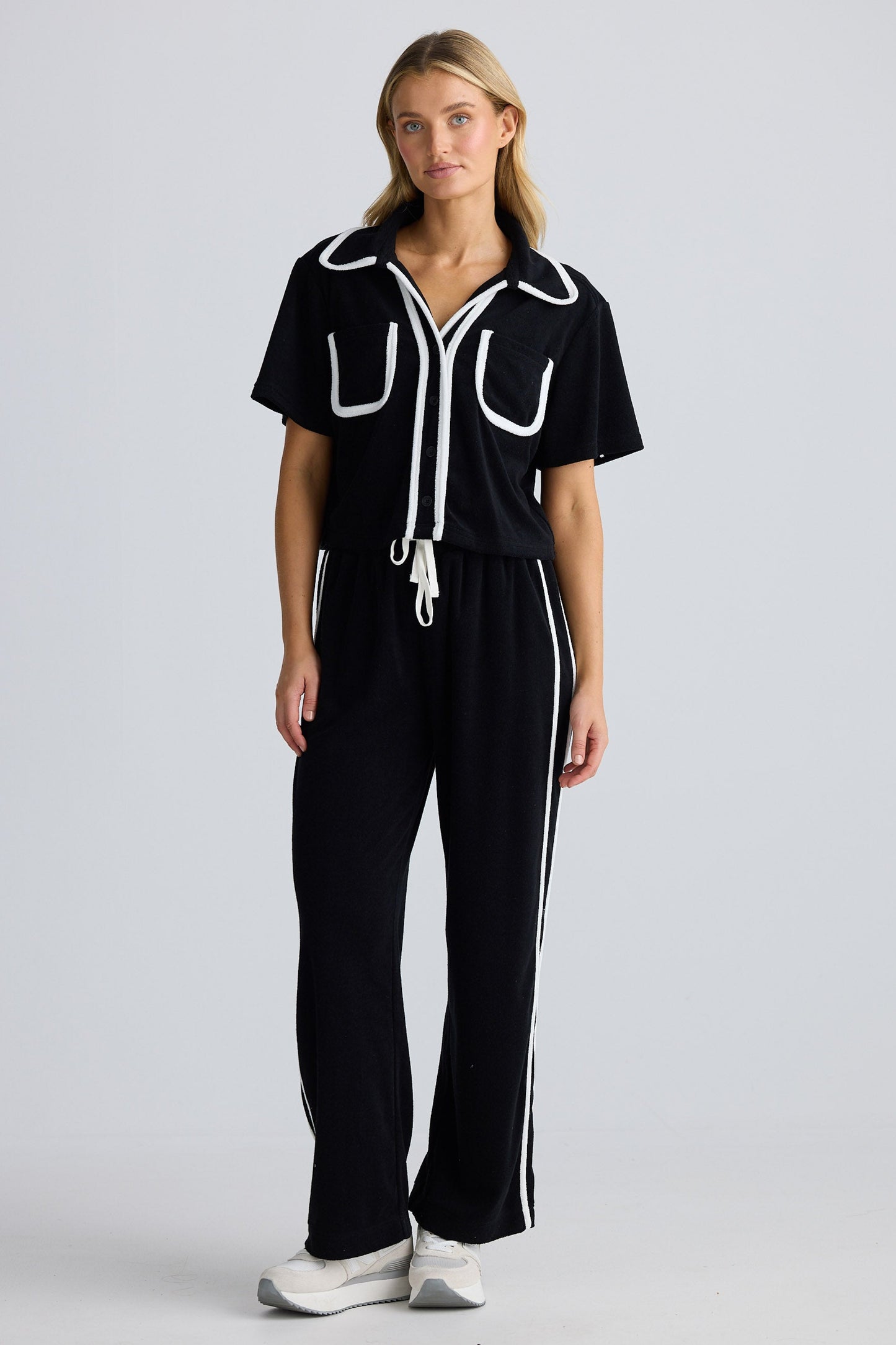 Woman wearing a black outfit with white accents on a plain background