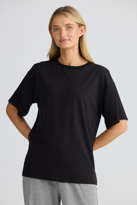 Woman wearing a black t-shirt and gray pants on a light gray background