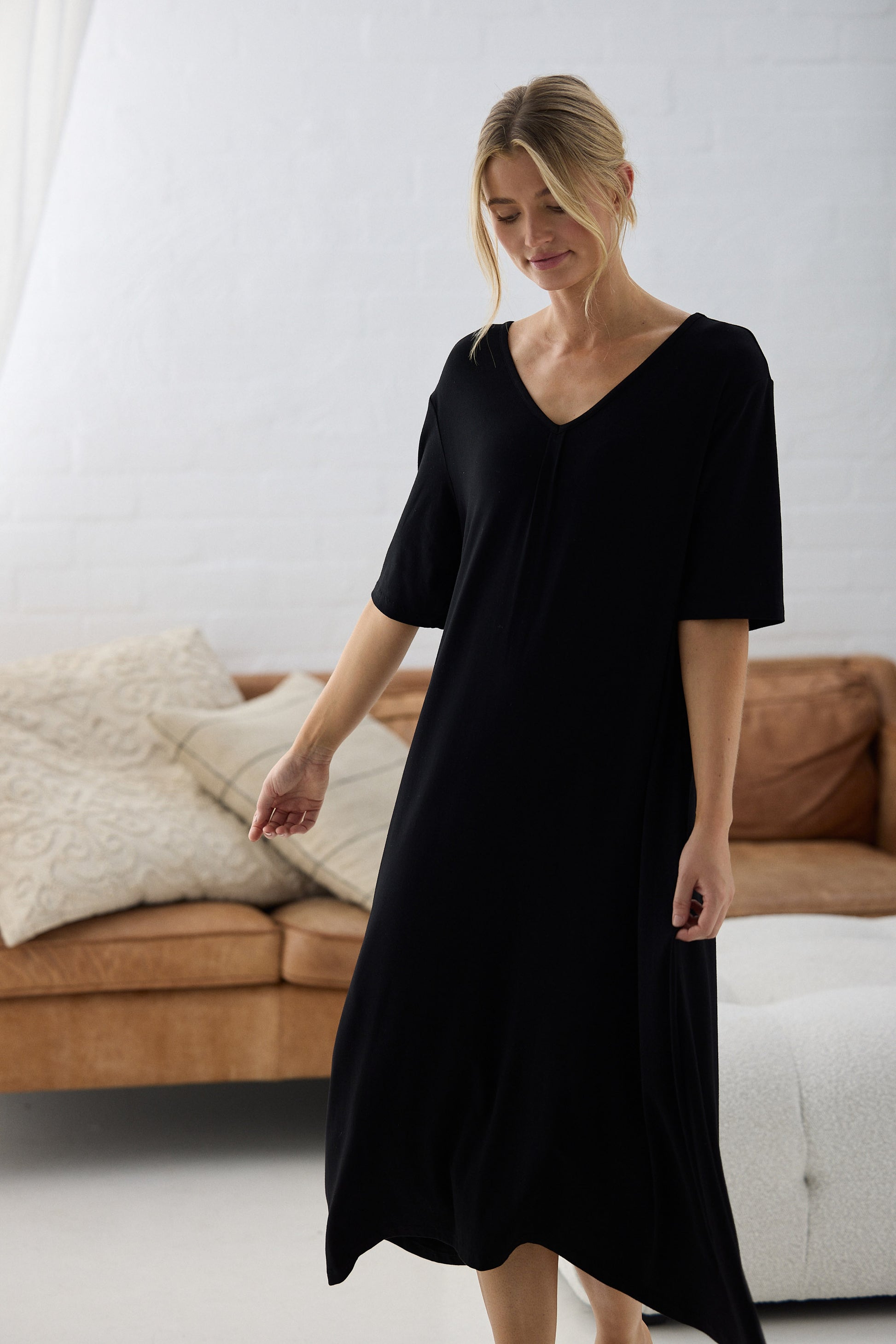 Woman wearing a black dress in a minimalistic living room.