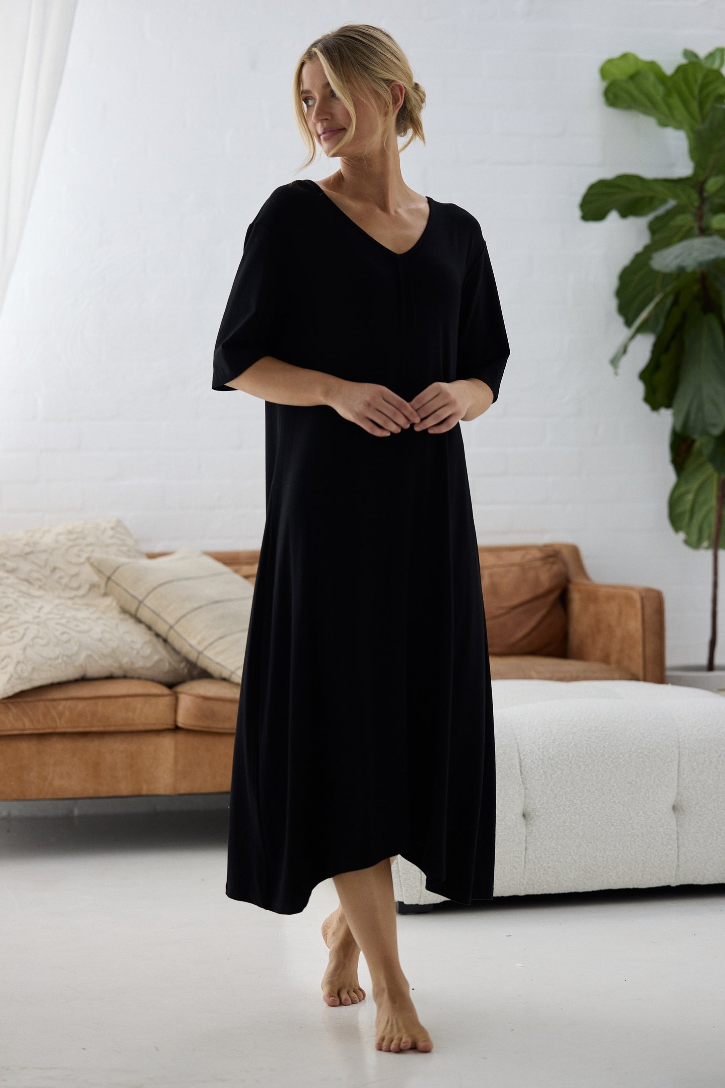 Woman wearing a black dress standing in a modern living room.