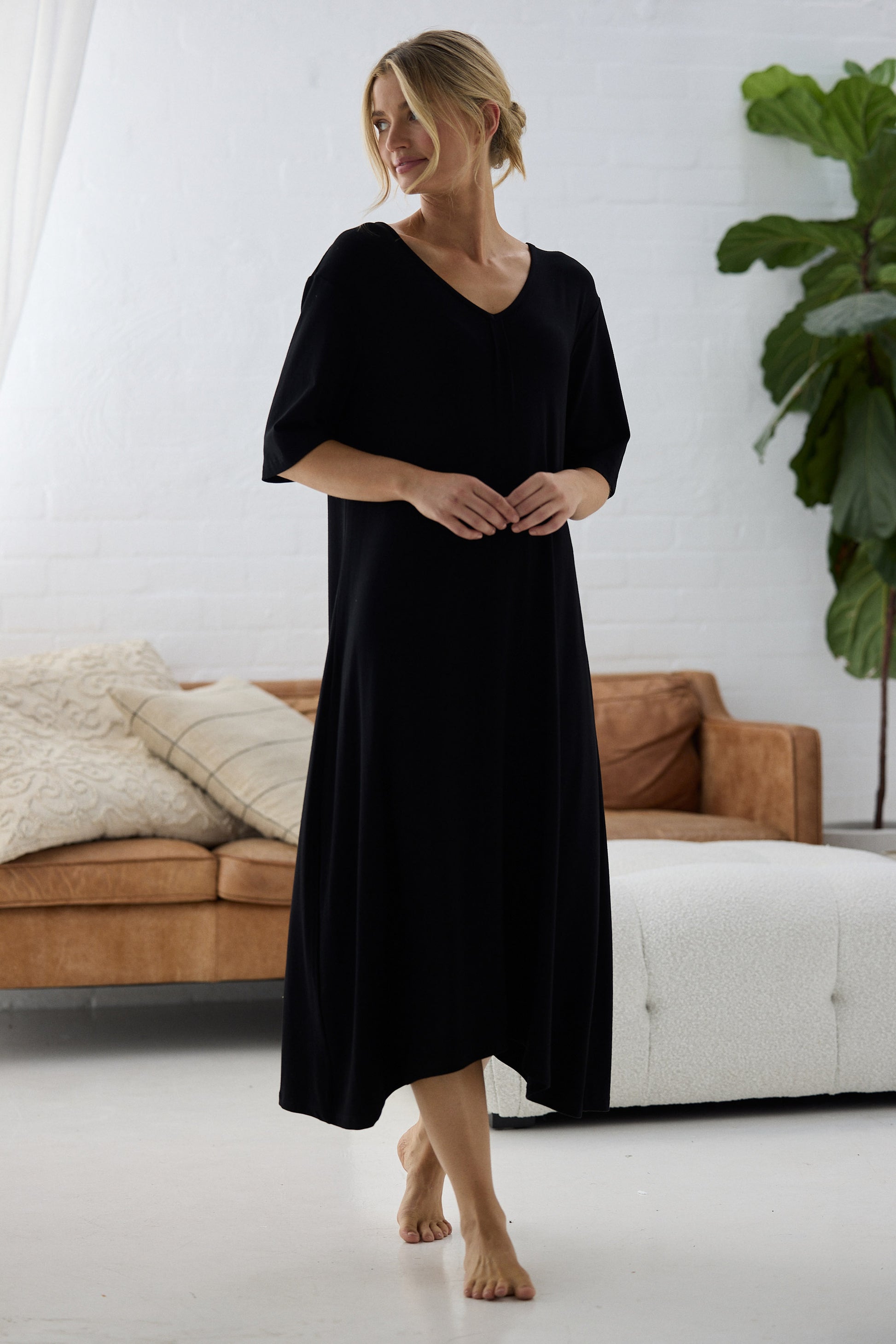 Woman wearing a black dress standing in a modern living room.