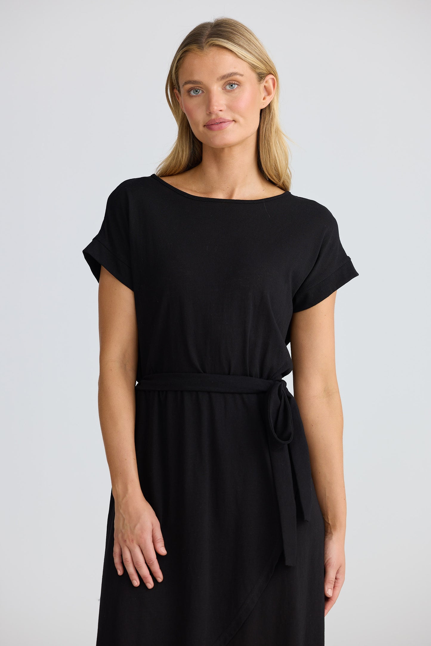 Woman wearing a black dress with a belt on a plain background