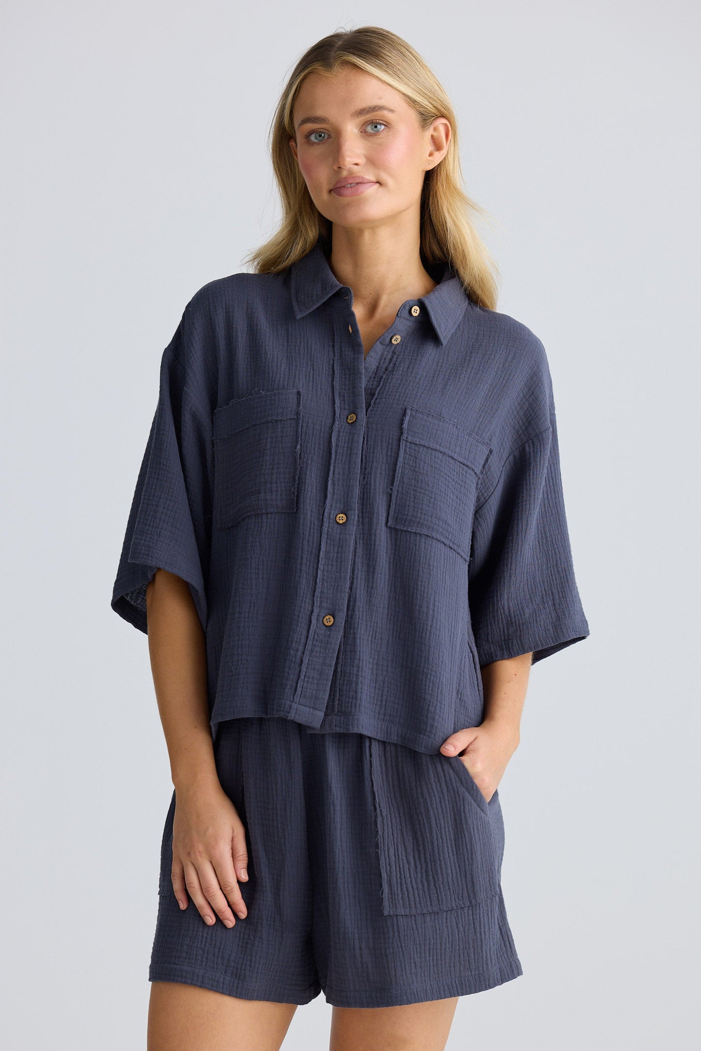 Woman wearing a navy blue shirt and shorts set on a light gray background