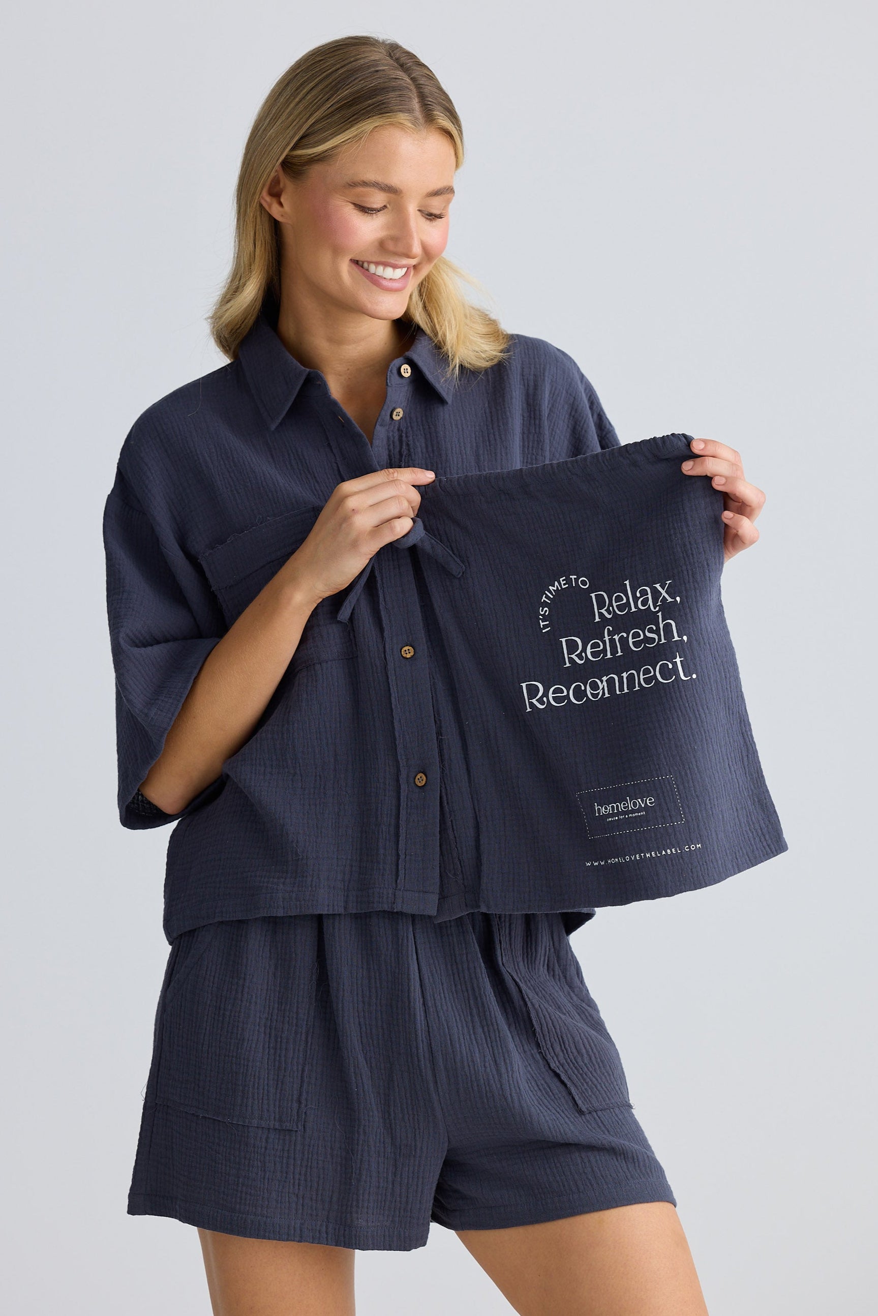 Woman holding a navy blue towel with text on a plain background