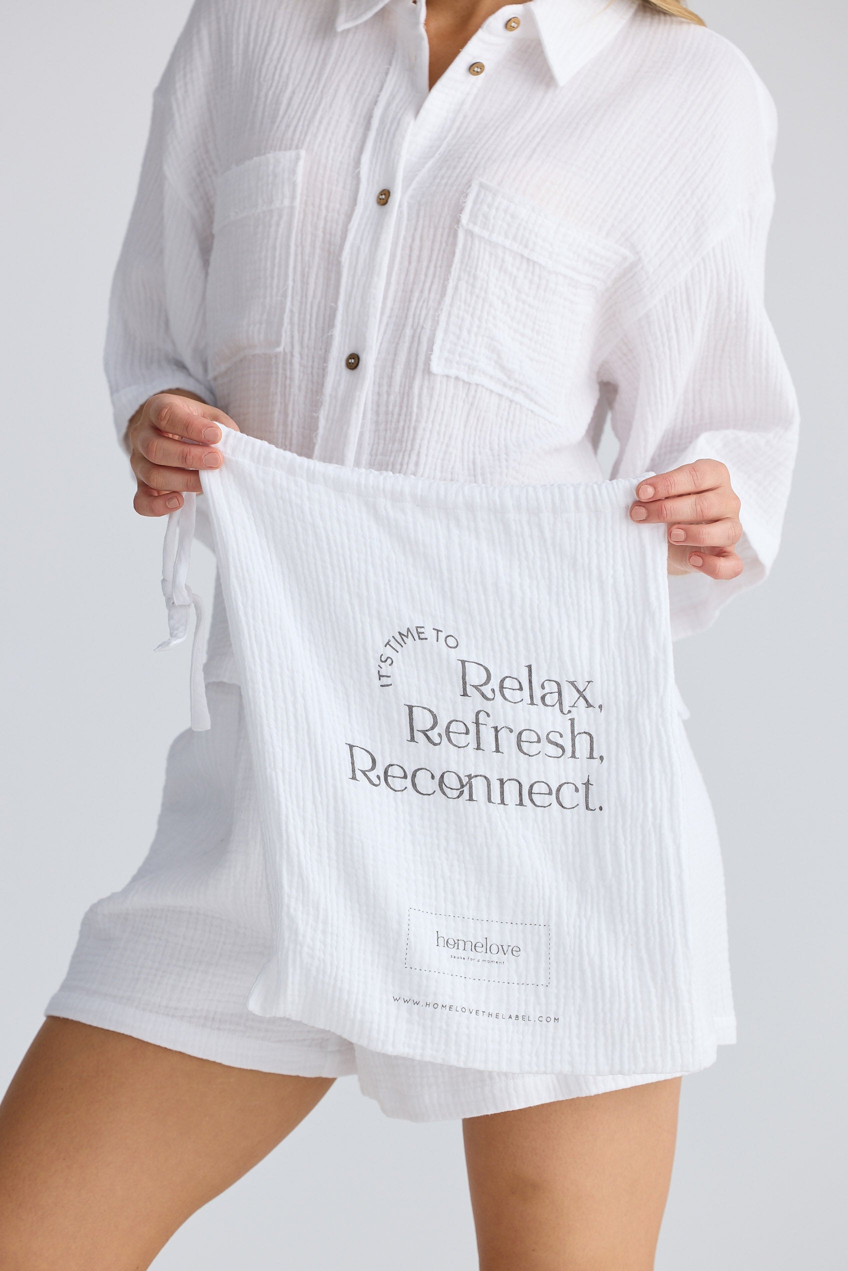 Person holding a white tote bag with text on a plain background