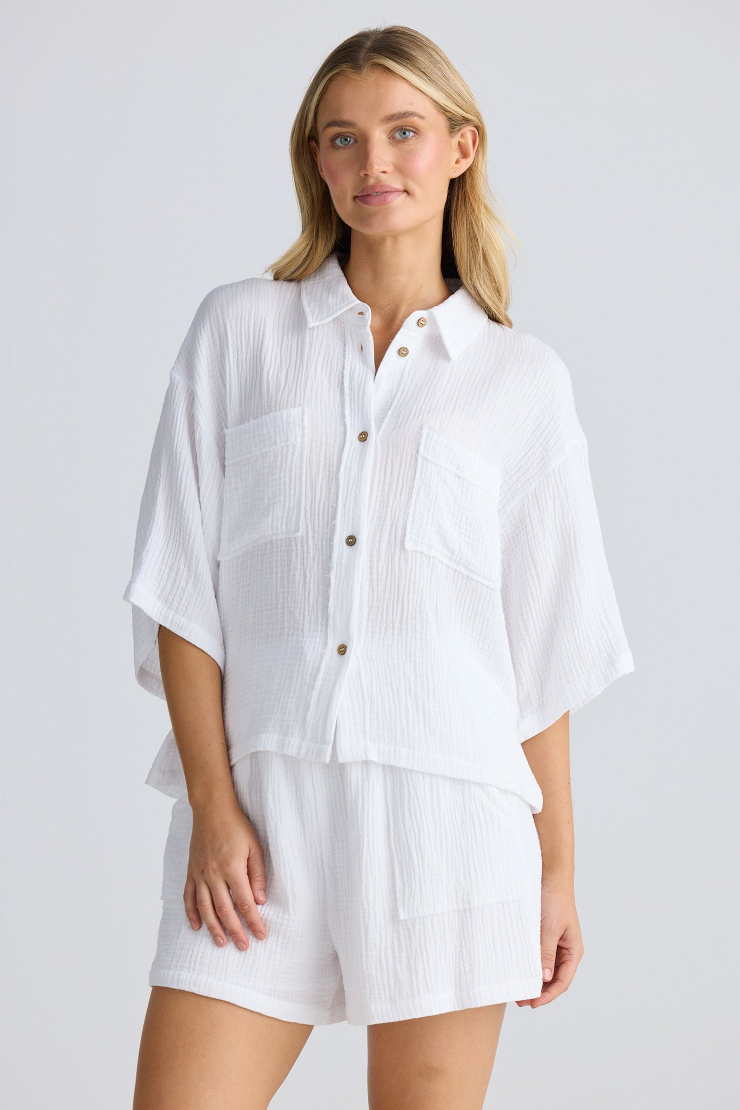 Woman wearing a white shirt and shorts on a plain background