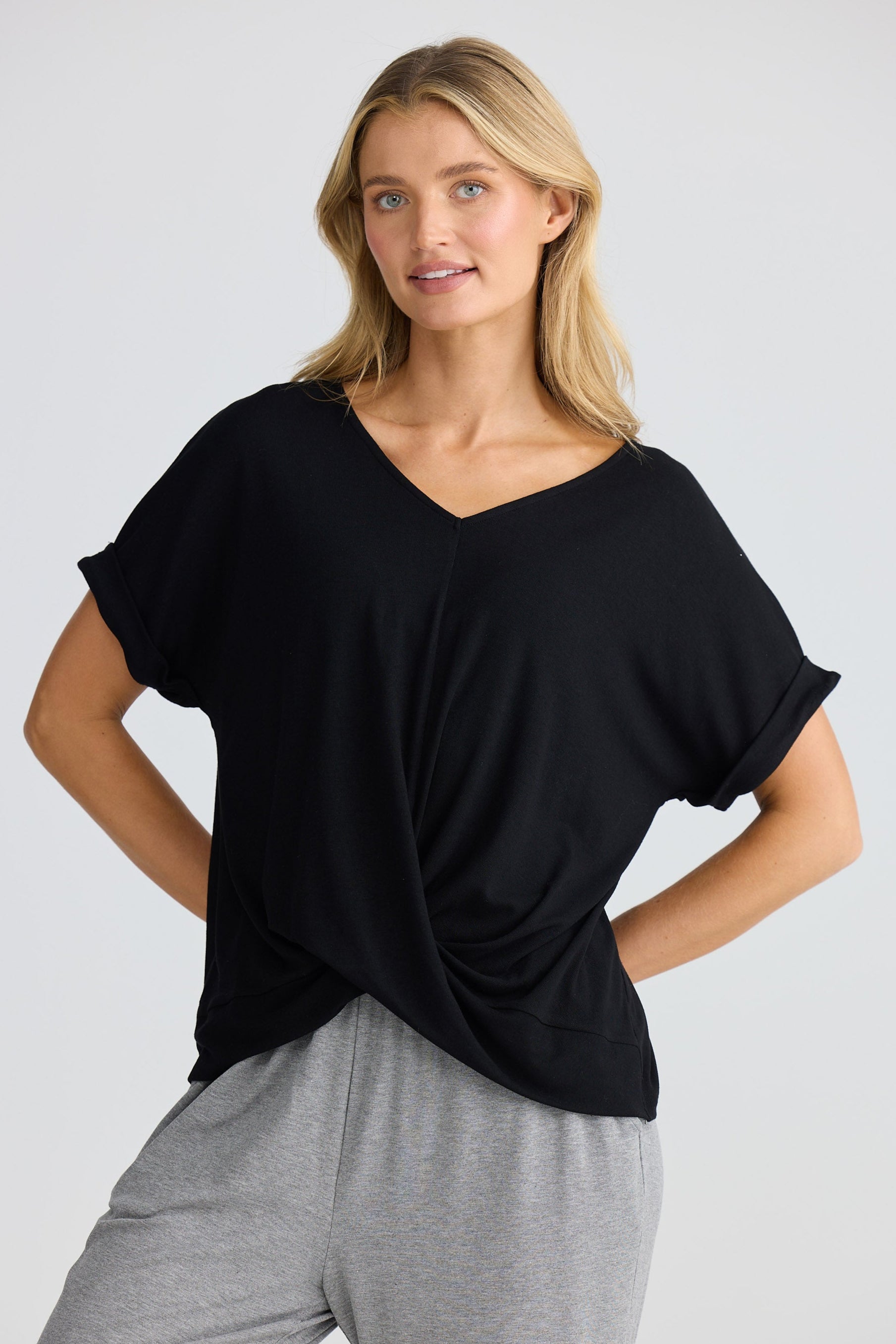 Woman wearing a black top and gray pants on a white background