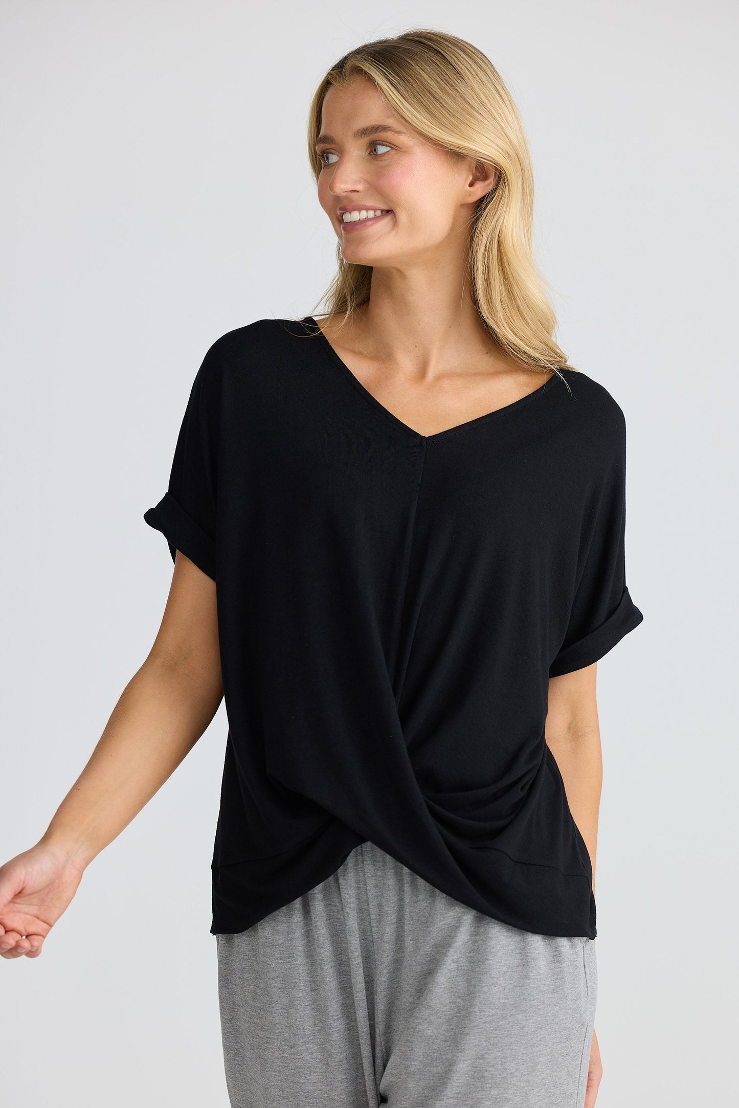 Woman wearing a black top and gray pants on a white background