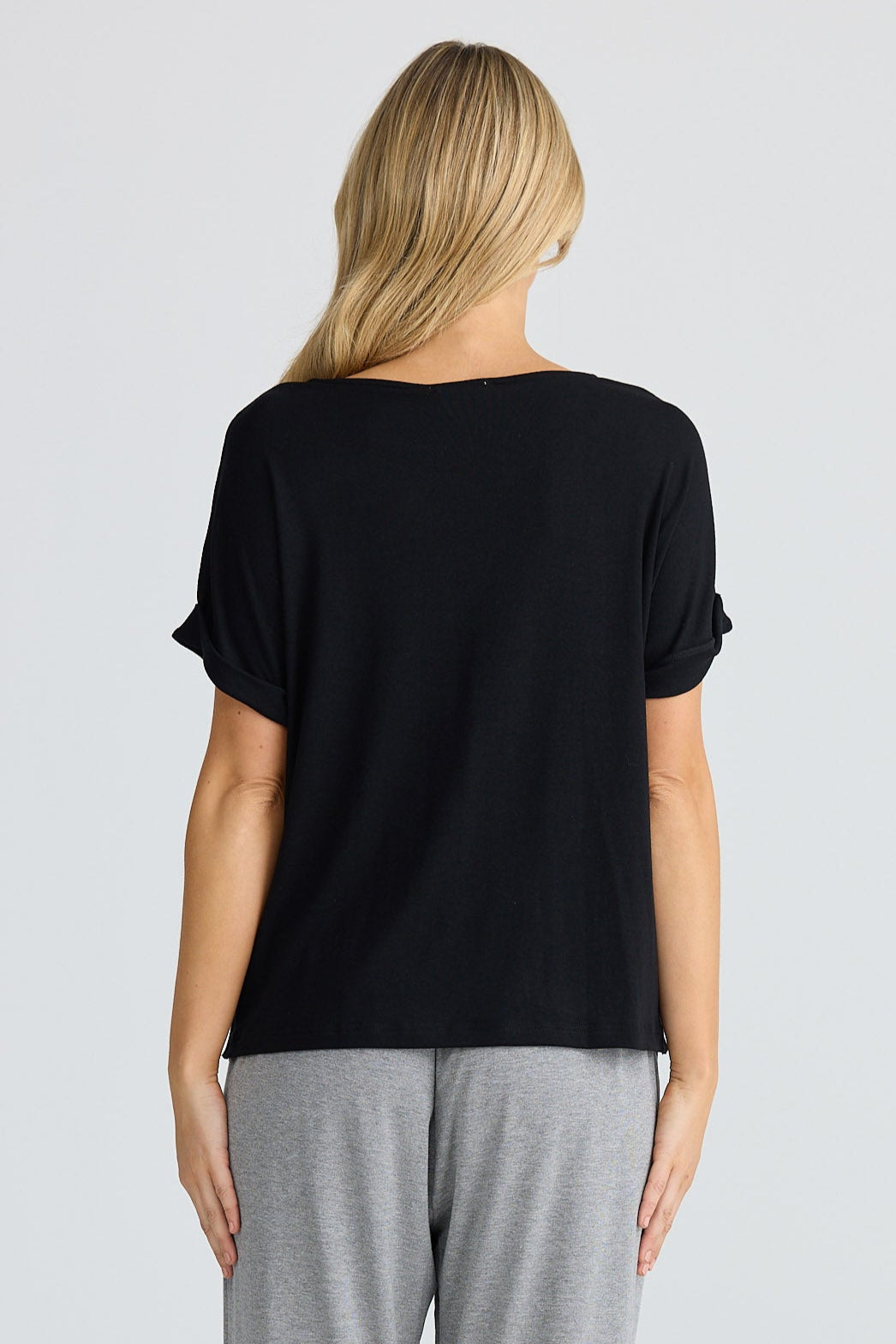 Woman wearing a black top and gray pants on a white background