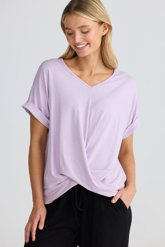 Woman wearing a light purple t-shirt and black pants on a white background