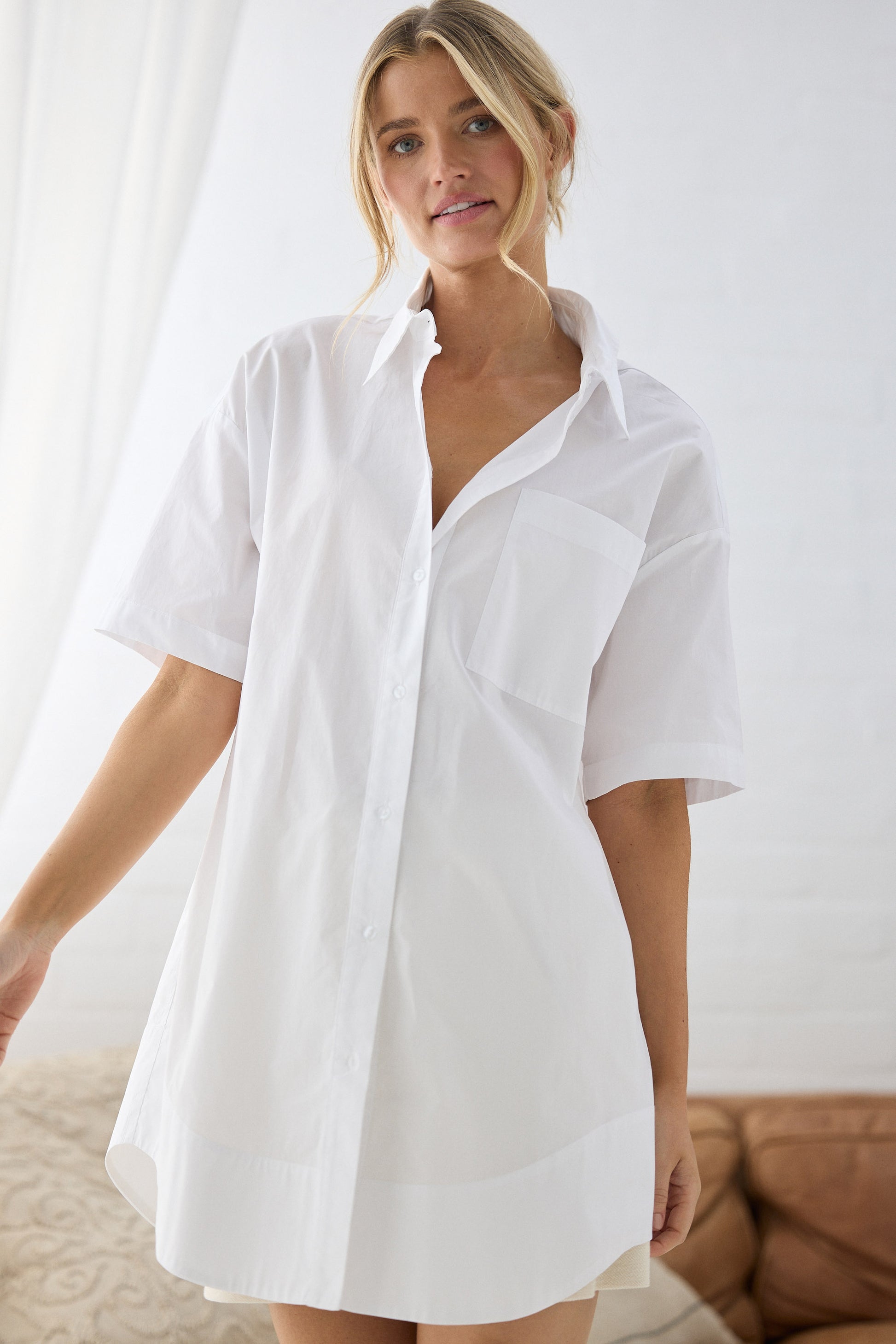 Woman wearing a white shirt dress against a neutral background