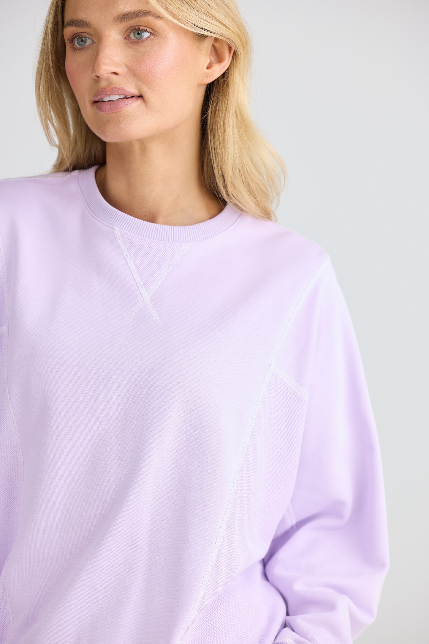 Woman wearing a light purple sweatshirt against a plain background