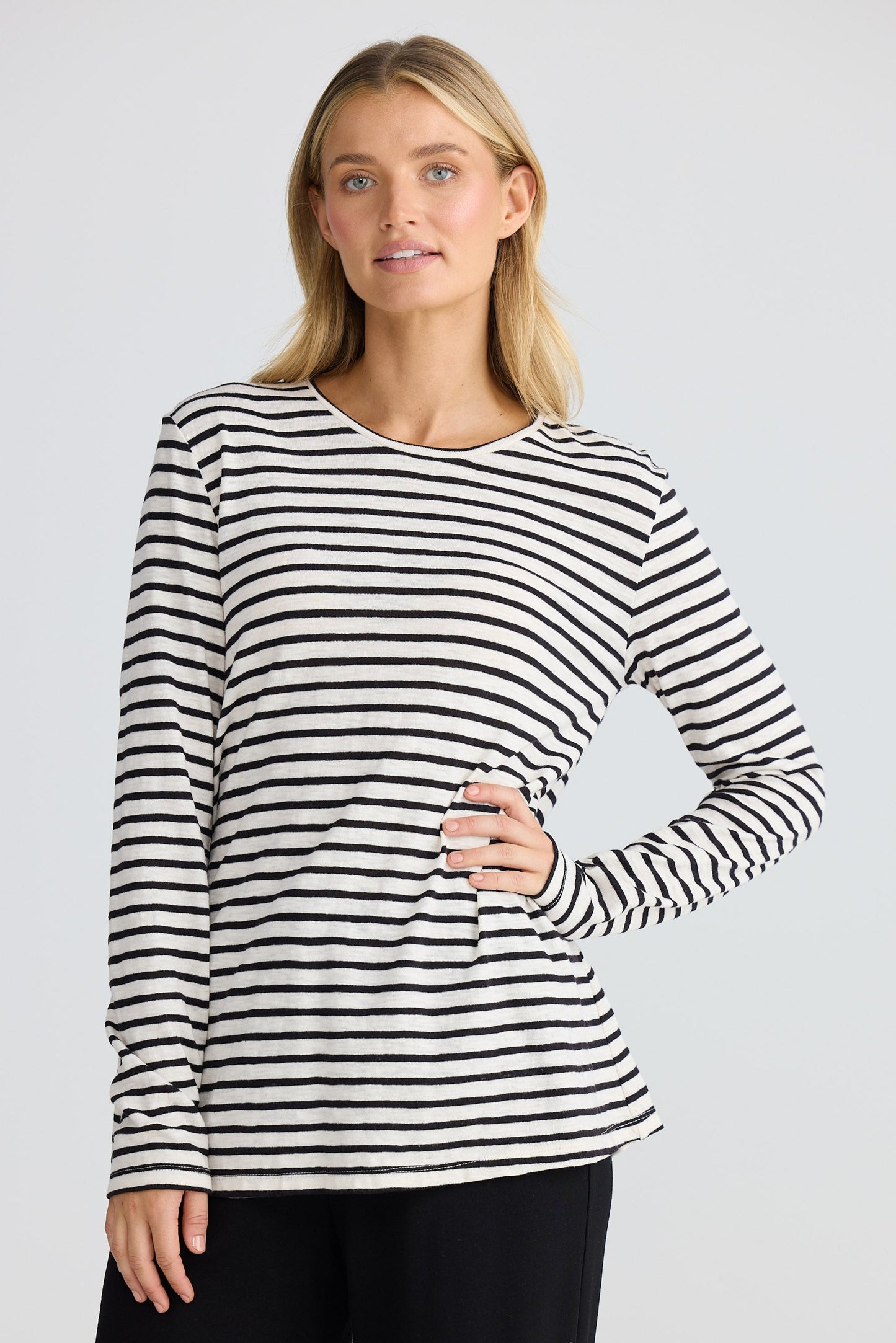 Woman wearing a black and white striped long-sleeve top on a plain background