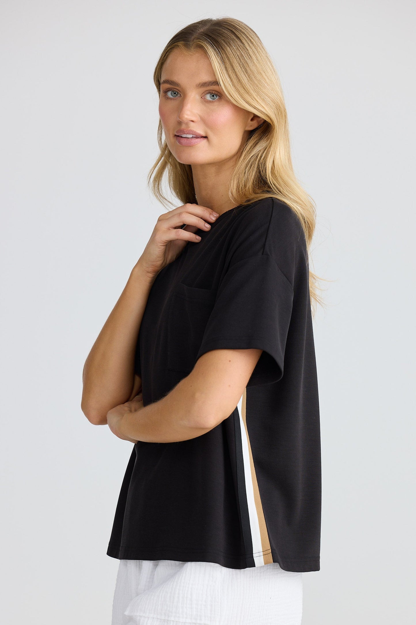 Woman wearing a black top and white shorts on a light gray background