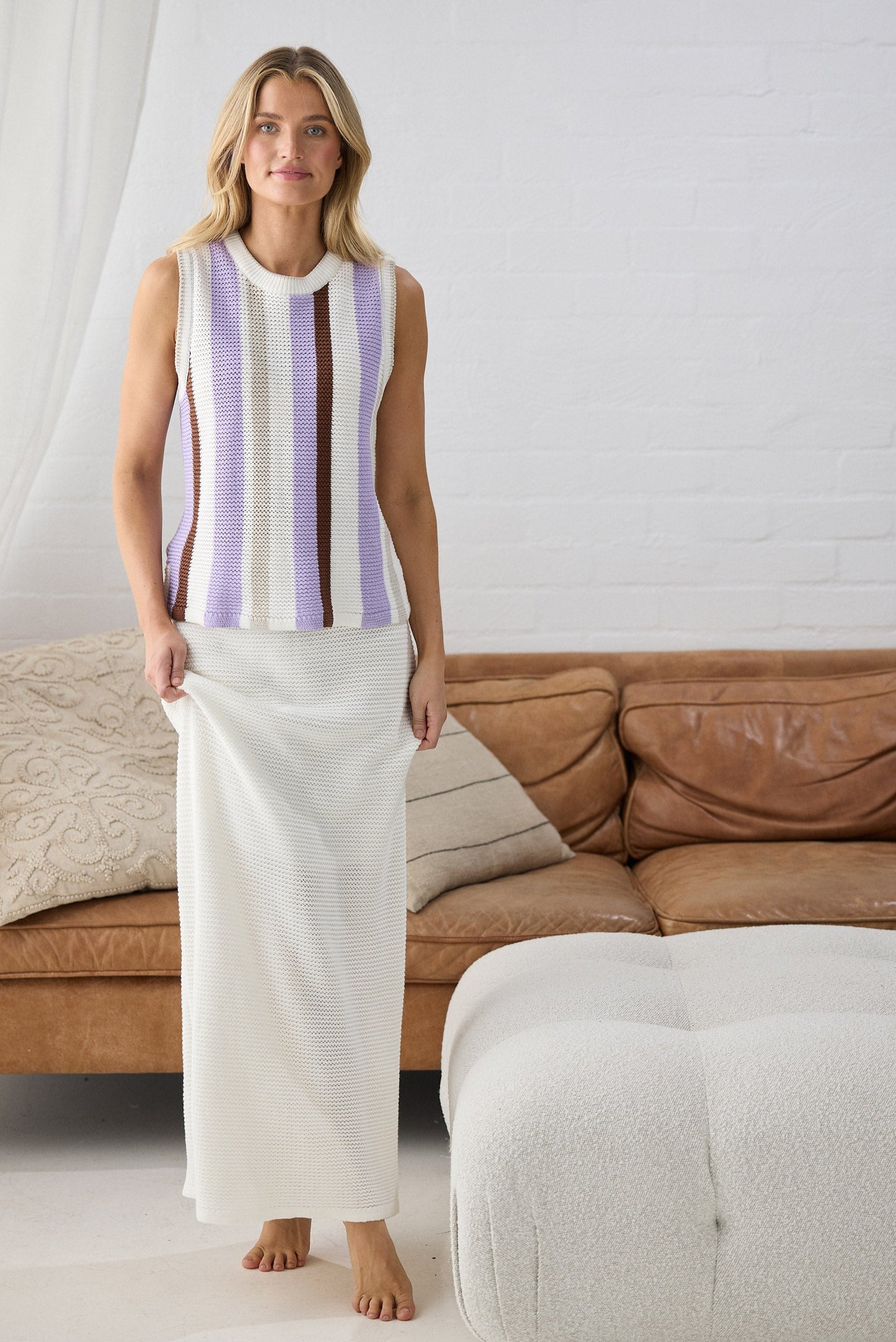 Woman wearing a striped top and white pants standing in a living room.