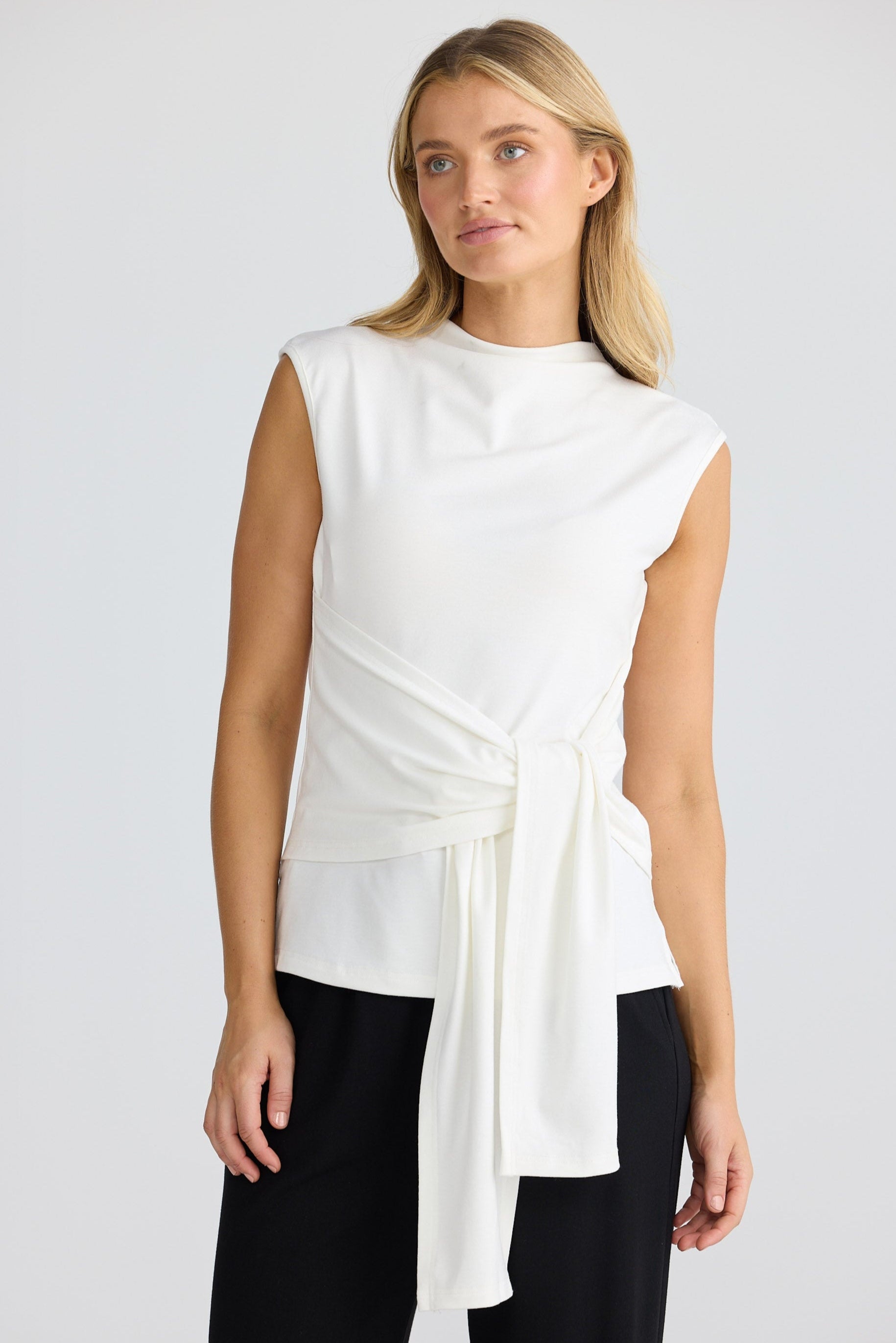 Woman wearing a white sleeveless top with a black skirt on a white background