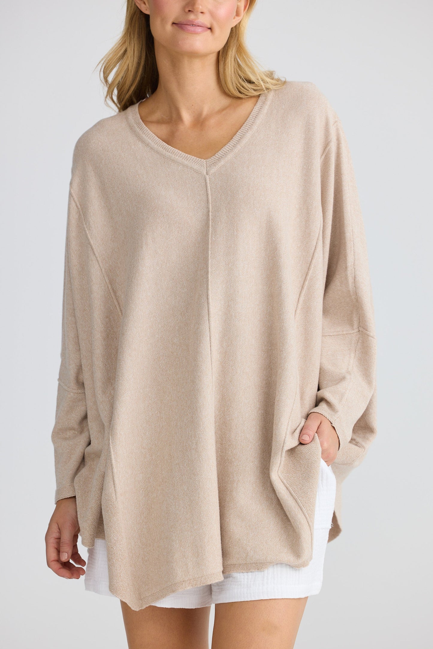Woman wearing a beige oversized sweater with a white background