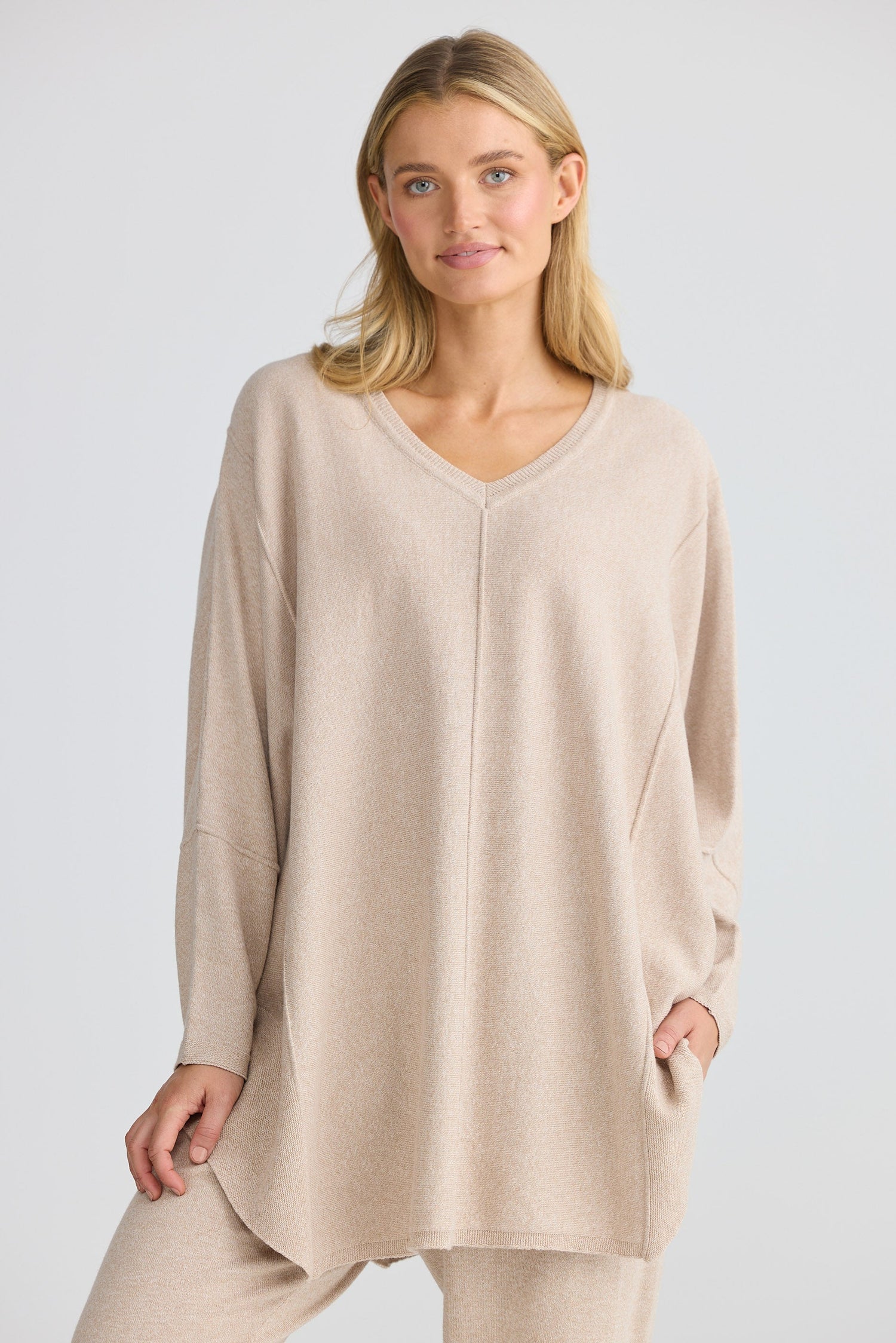 Woman wearing a beige long-sleeve top and pants on a white background