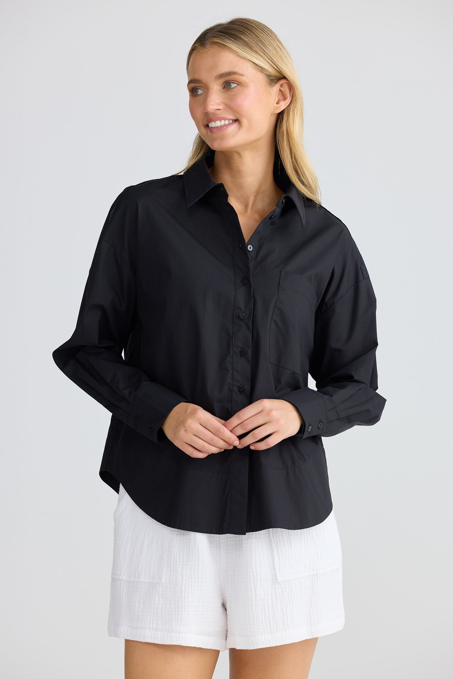 Woman wearing a black shirt and white shorts on a plain background