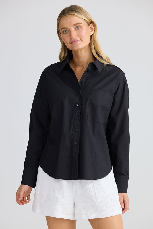 Woman wearing a black shirt and white shorts on a plain background