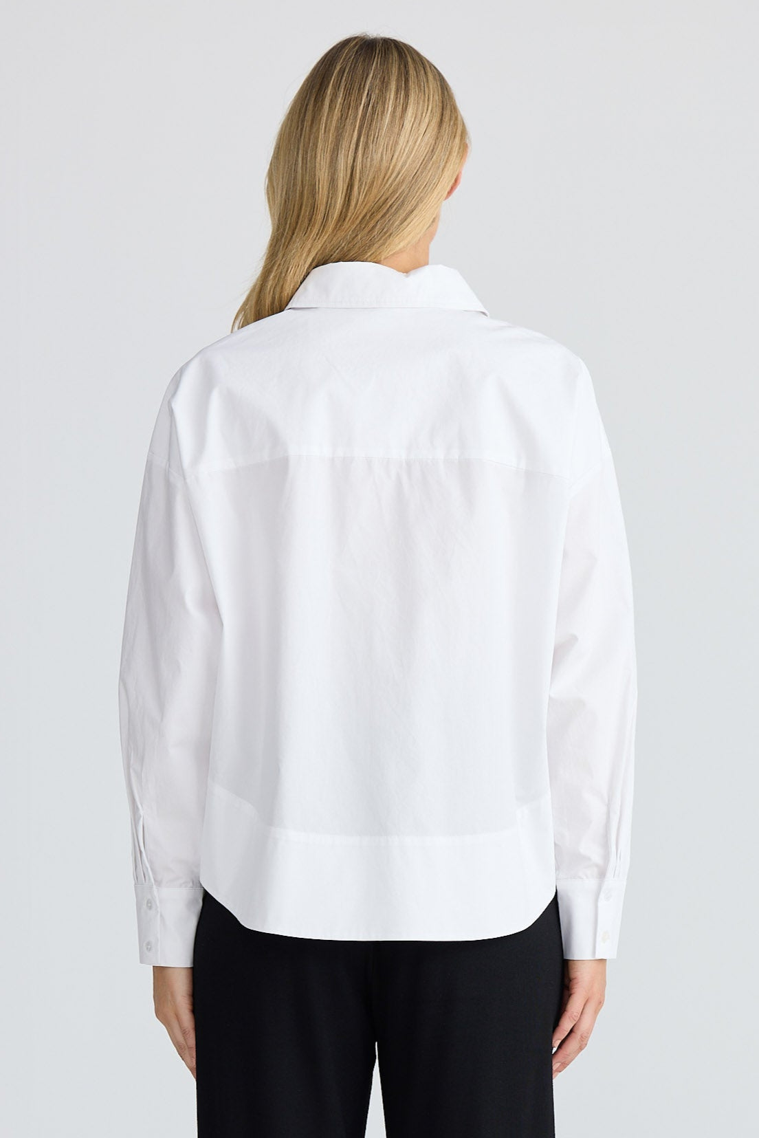 Person wearing a white shirt and black pants on a white background